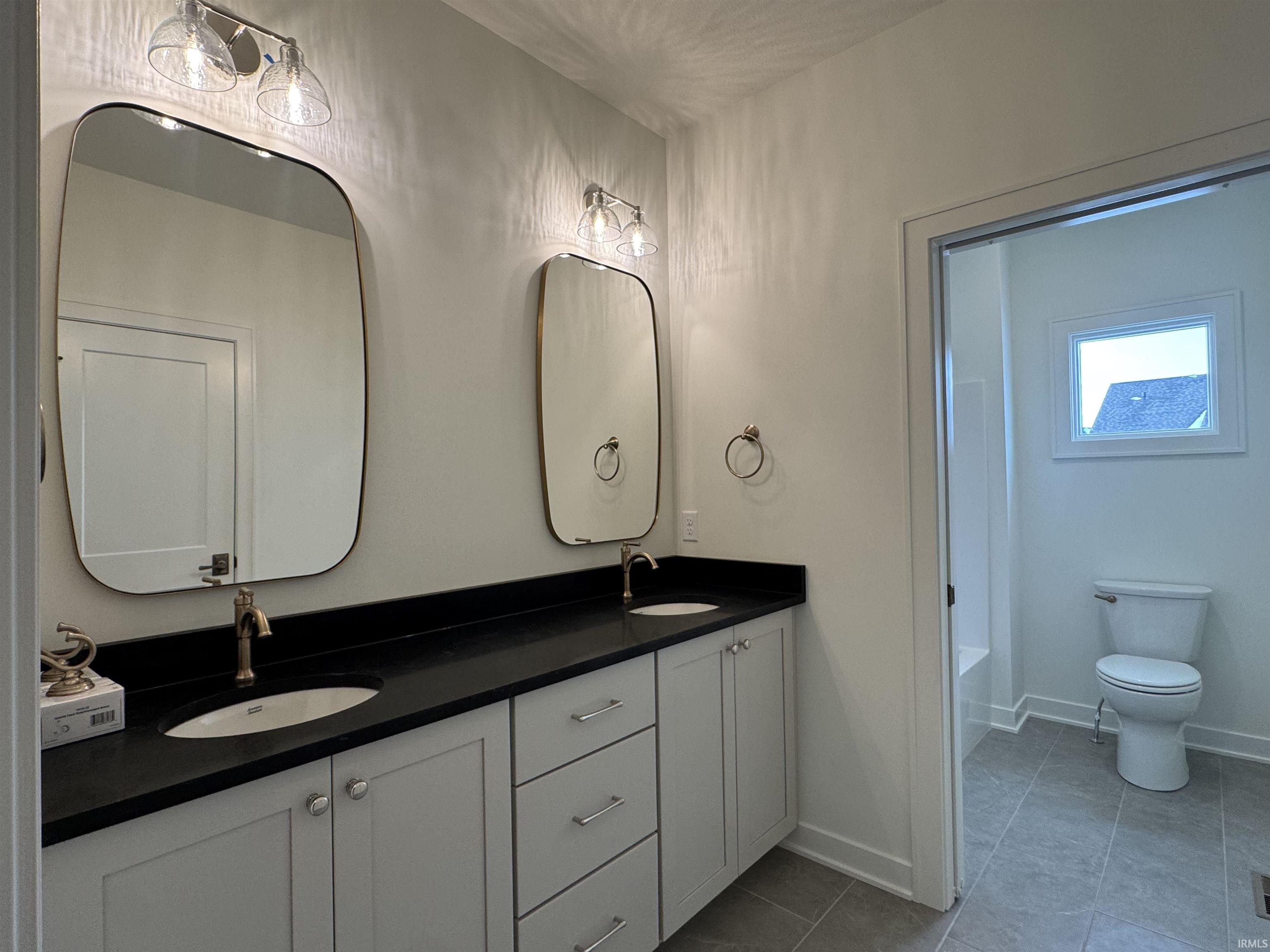 Bathroom with double vanity and light tile patterned floors