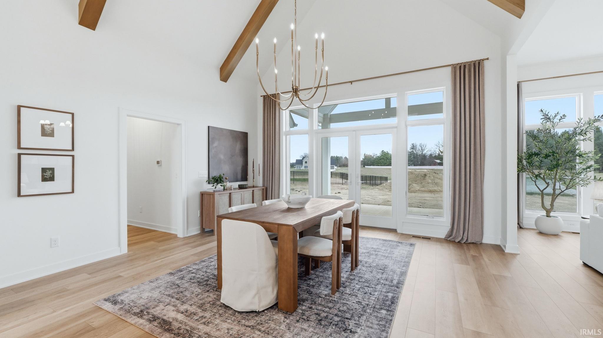 Dining room with vaulted ceiling, a chandelier, light wood-type flooring, and plenty of natural light