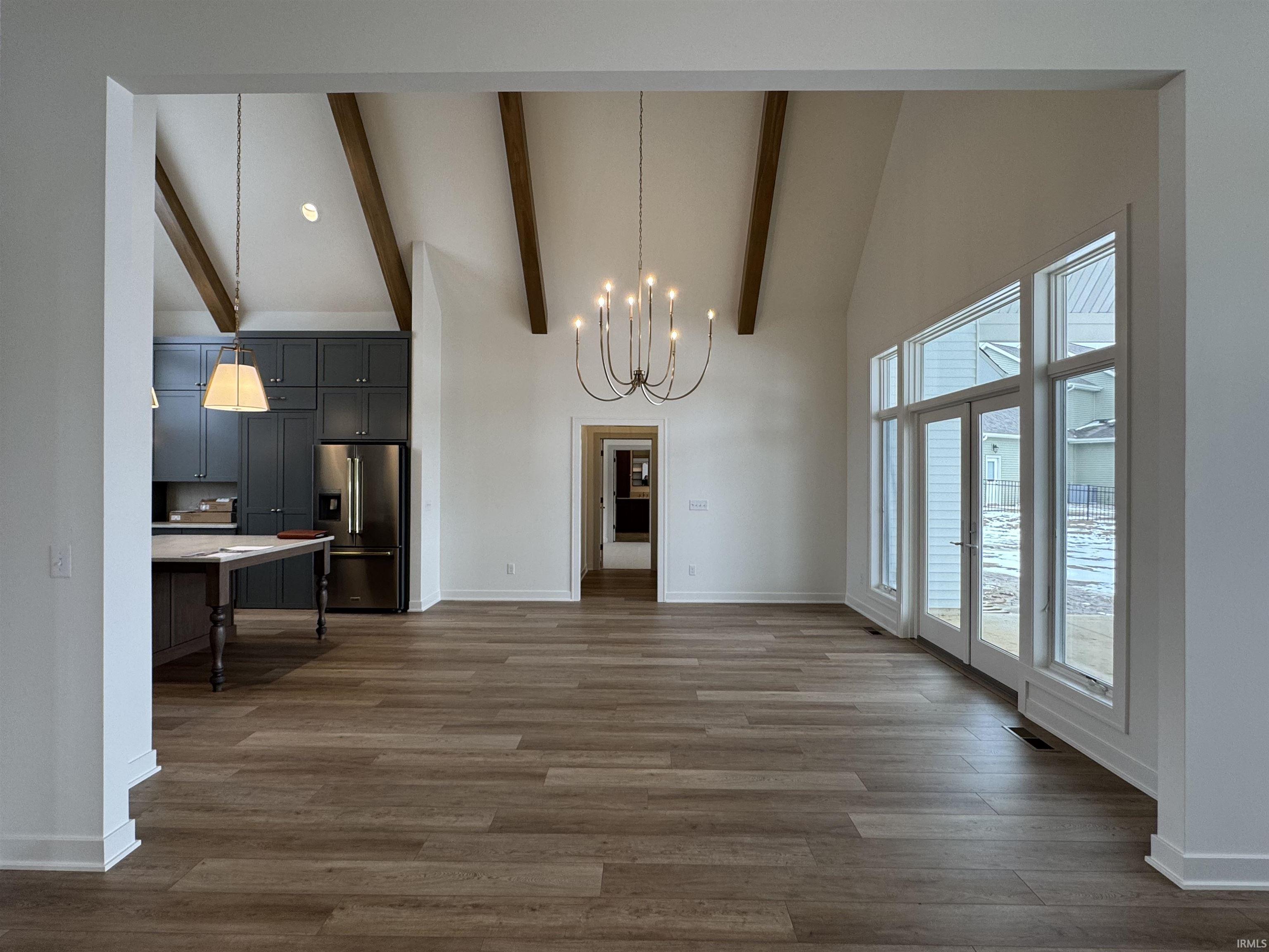 Unfurnished dining area with hanging lights, dark wood finished floors, and vaulted ceiling