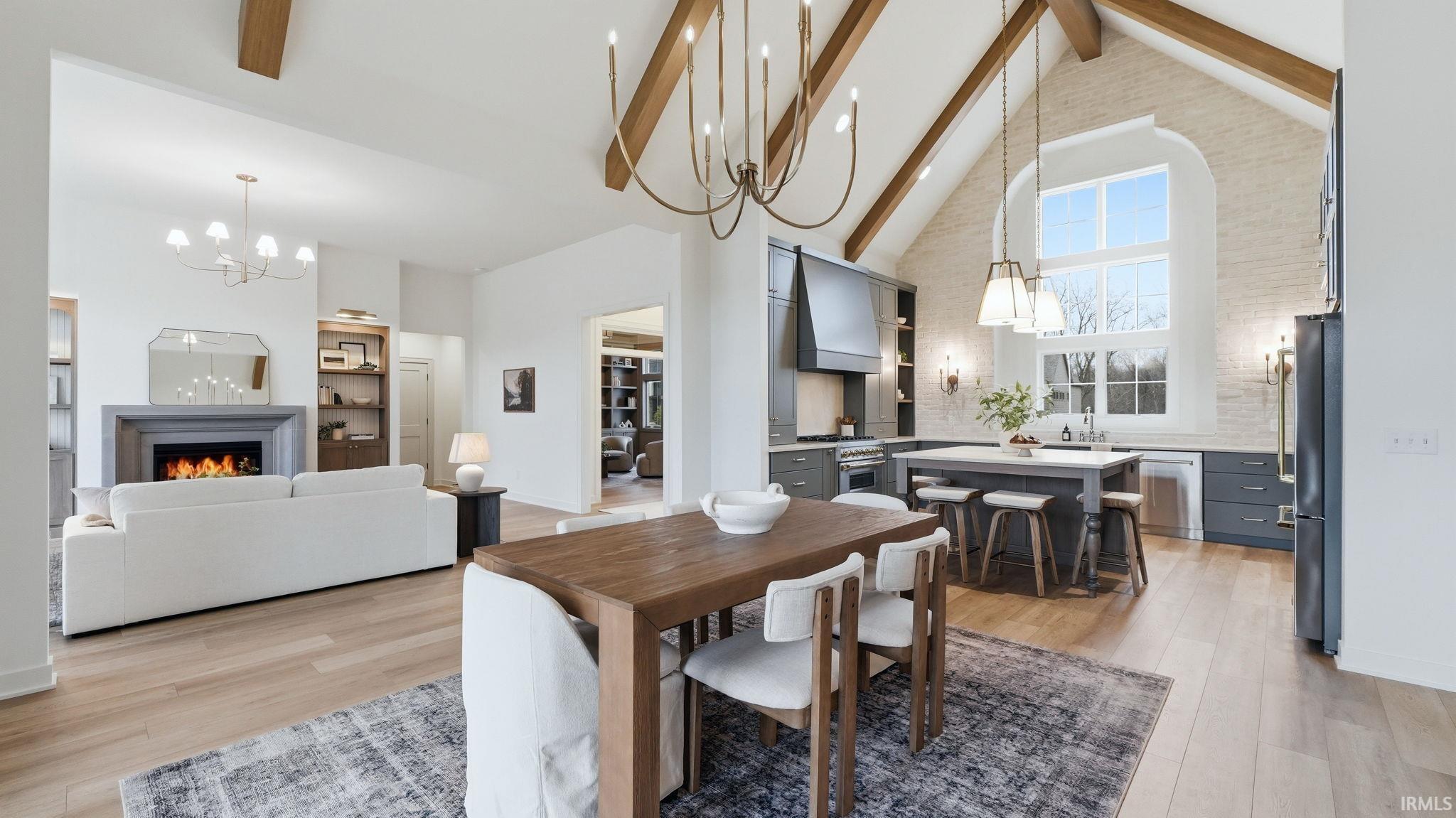 Dining space featuring hanging lights, a warm lit fireplace, and light wood finished floors