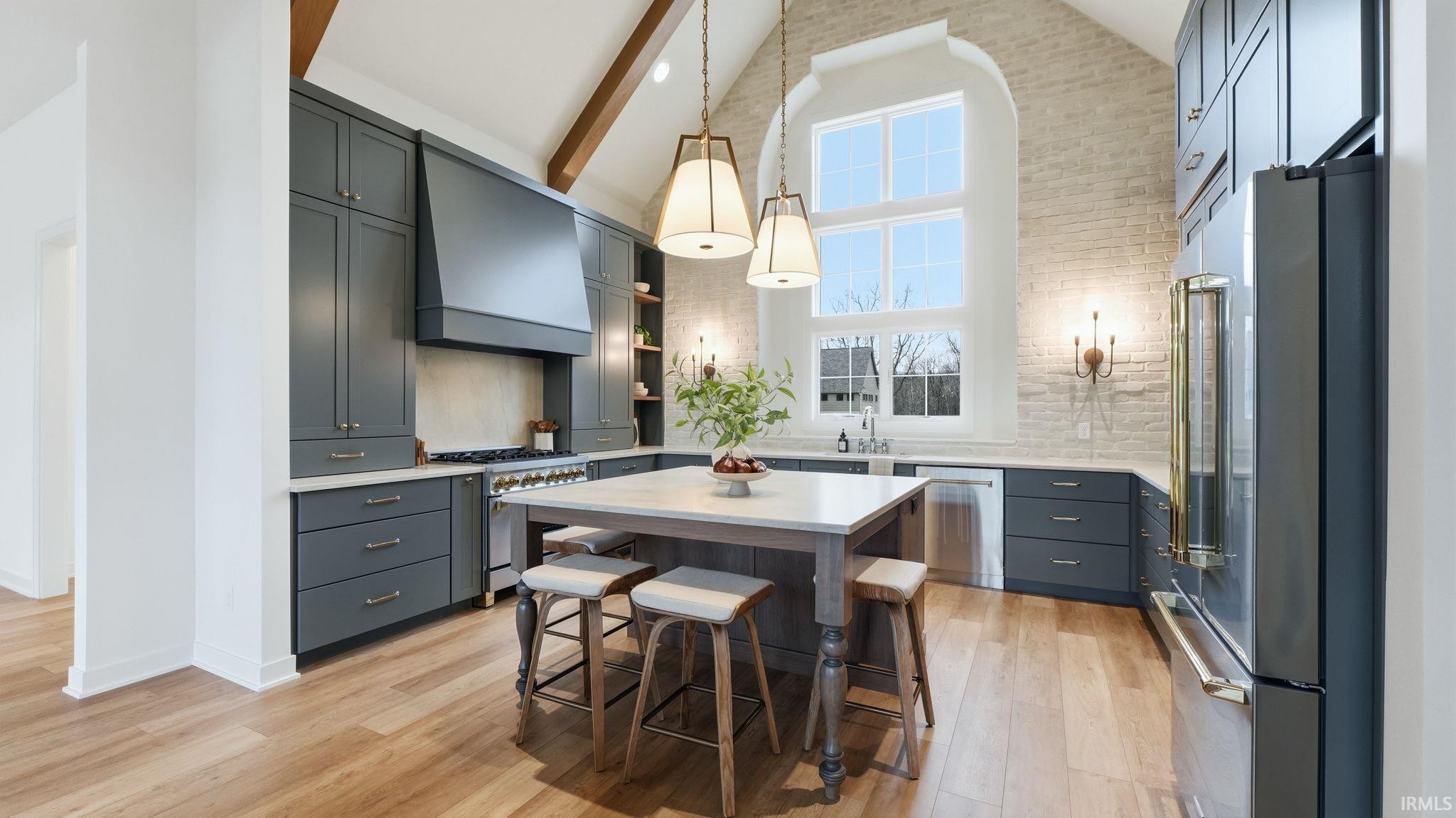 Kitchen featuring lofted ceiling, high quality appliances, a kitchen breakfast bar, light wood-style floors, and hanging light fixtures