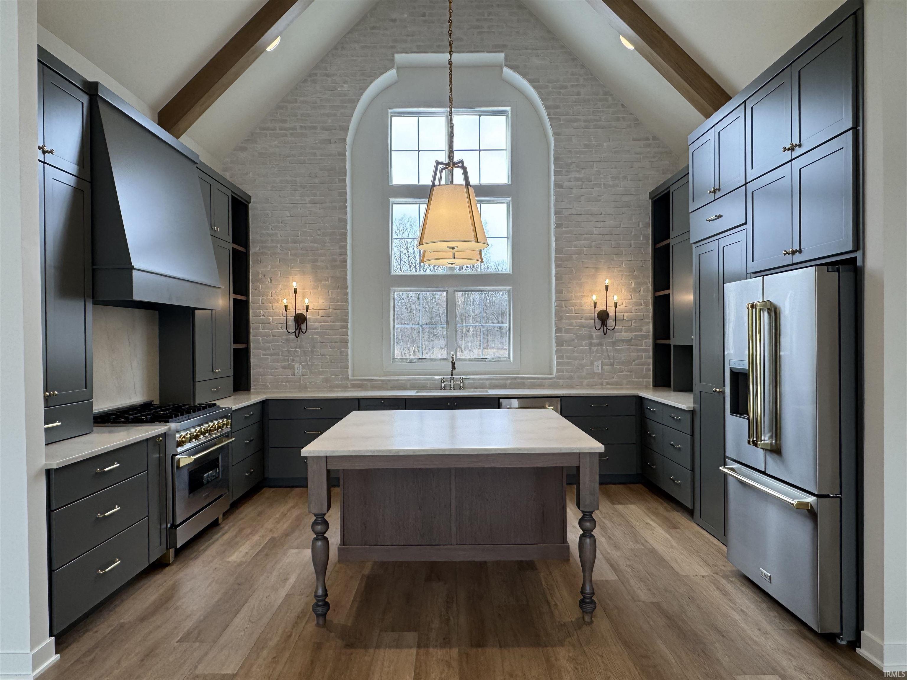 Kitchen featuring high end appliances, open shelves, dark wood-type flooring, hanging light fixtures, and brick wall