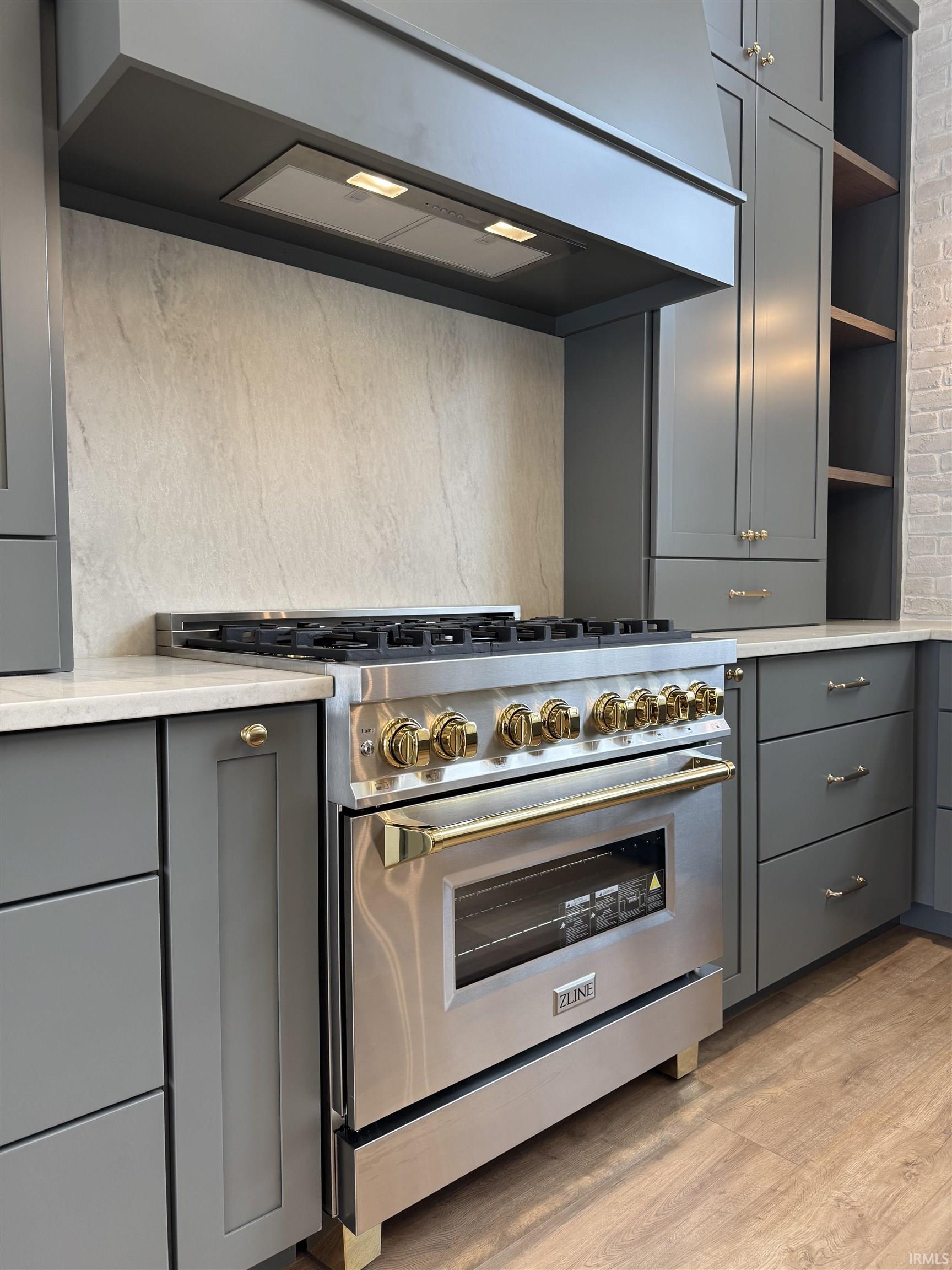 Kitchen featuring gray cabinetry, stainless steel range, open shelves, and light wood-style floors