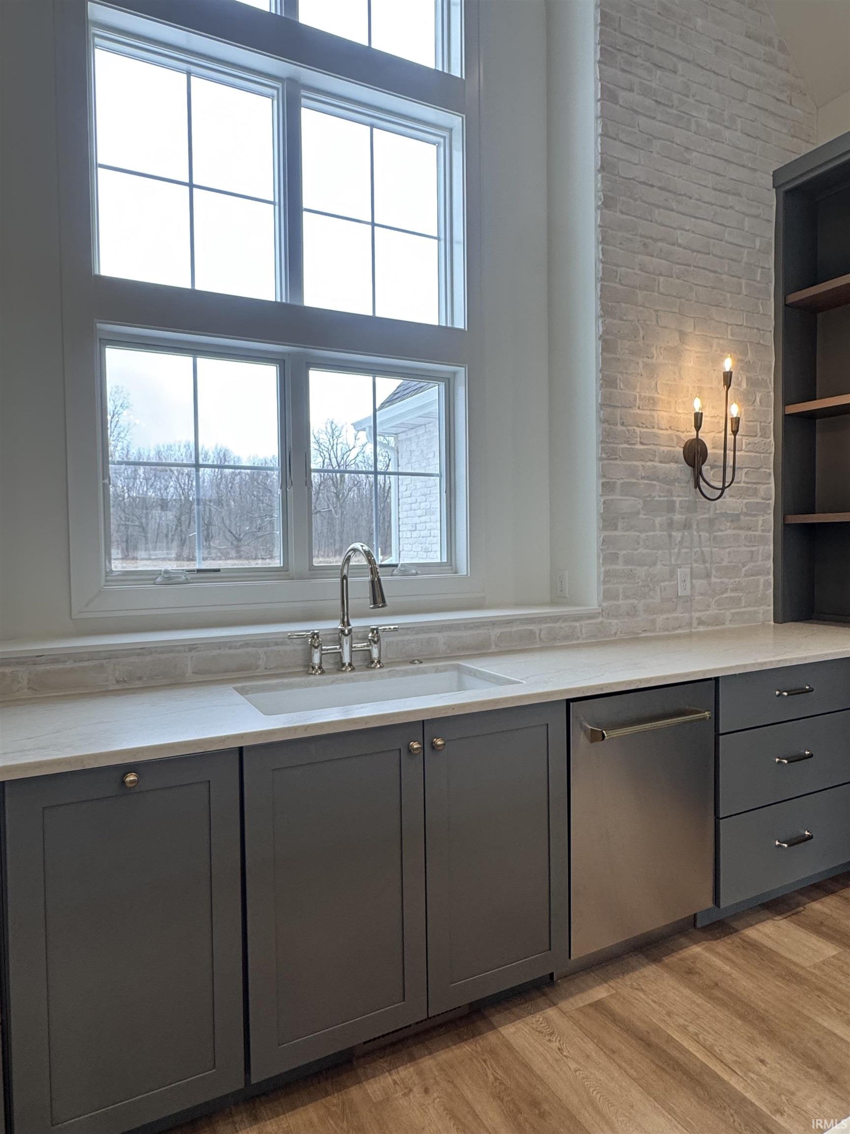 Kitchen featuring gray cabinetry, dishwasher, light wood-type flooring, open shelves, and light stone countertops