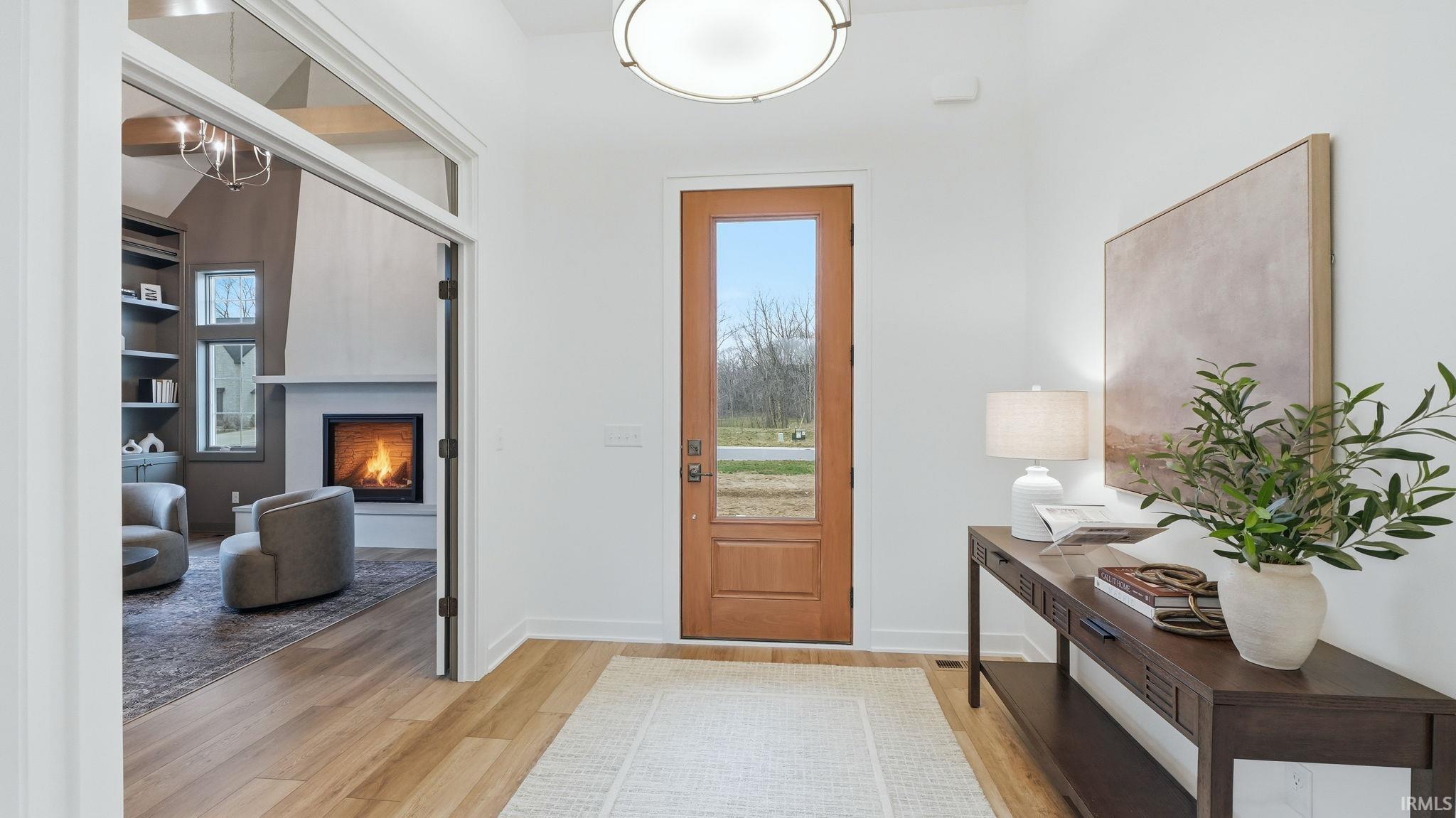 Entryway featuring a warm lit fireplace and light wood-style floors