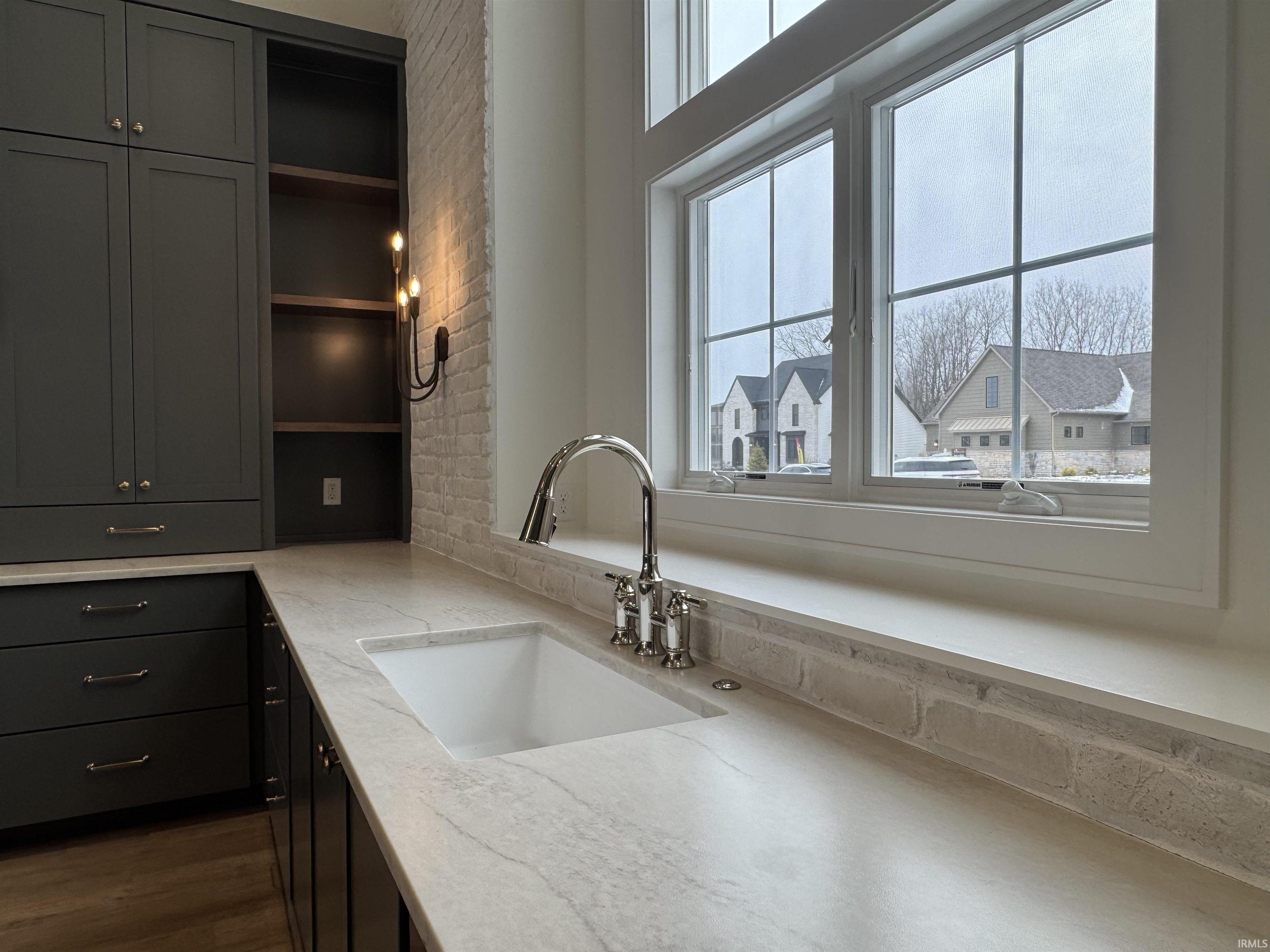 Kitchen featuring open shelves, light stone countertops, dark cabinets, and dark wood-style floors