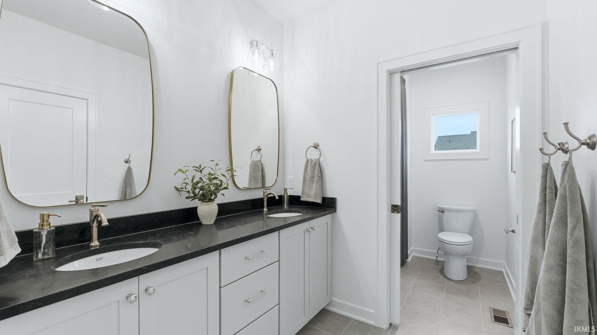 Full bath with double vanity and light tile patterned flooring