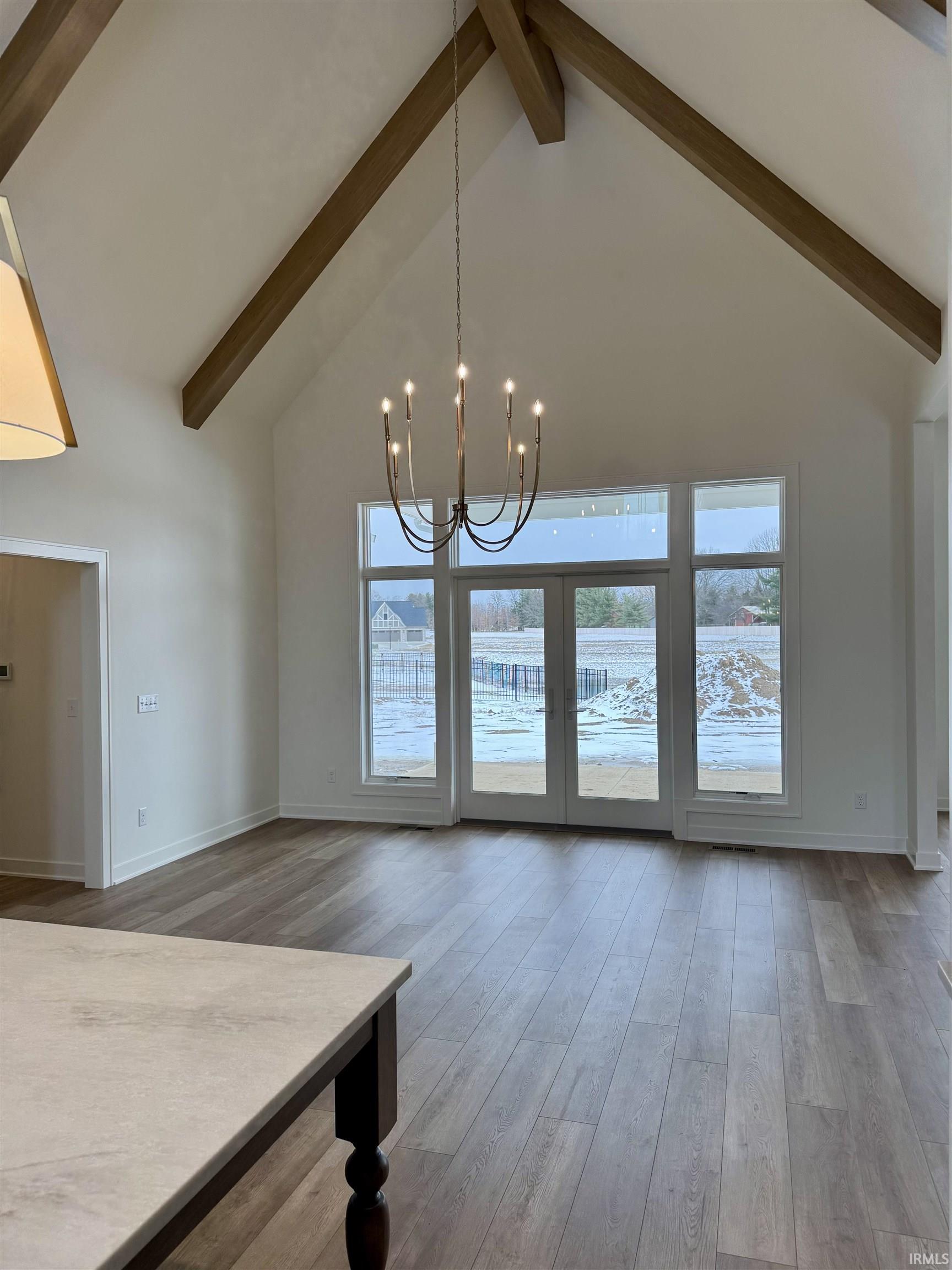 Unfurnished dining area with hanging lights, light wood finished floors, and lofted ceiling