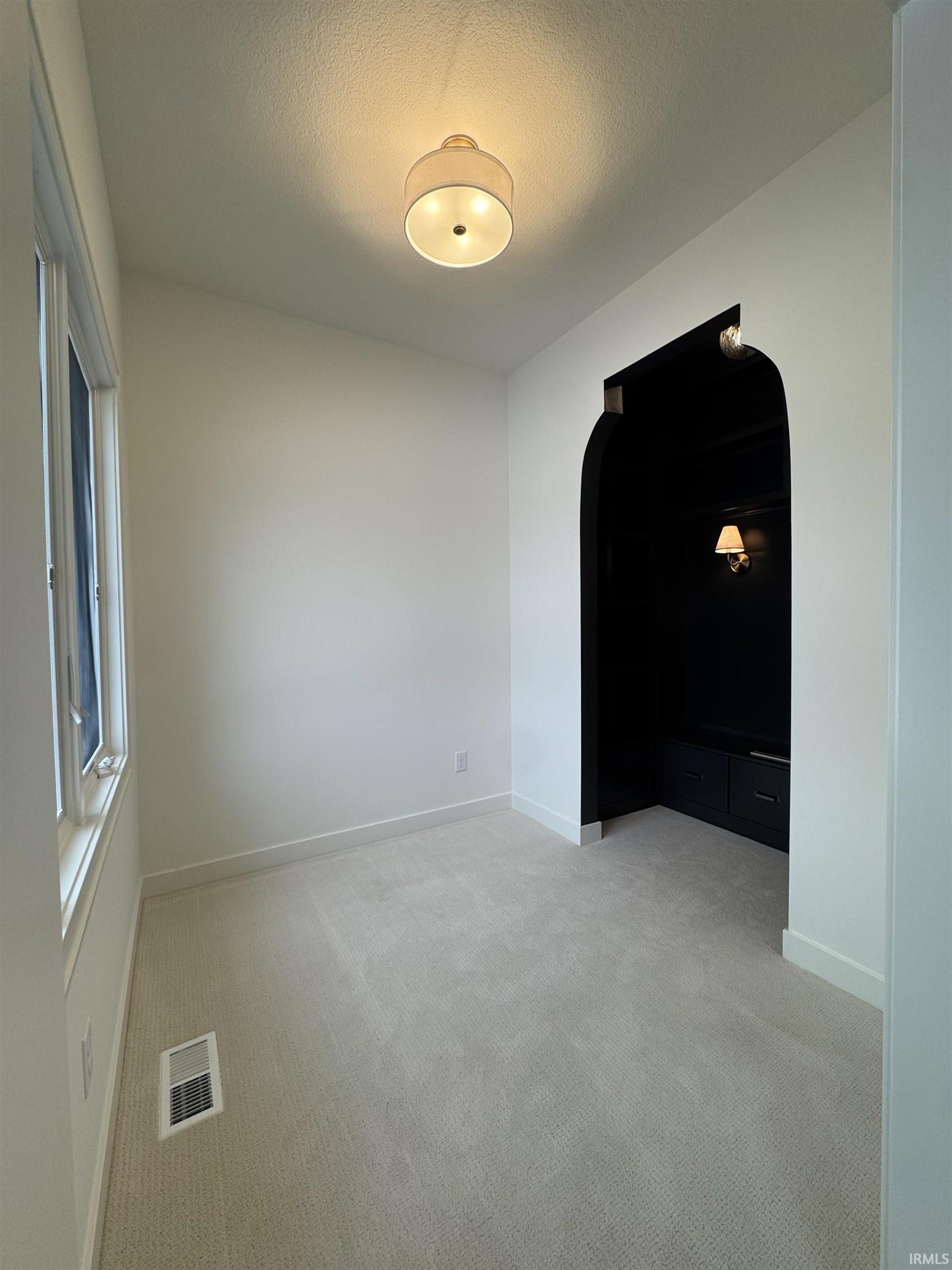 Sitting room with arched walkways, light colored carpet, and a textured ceiling