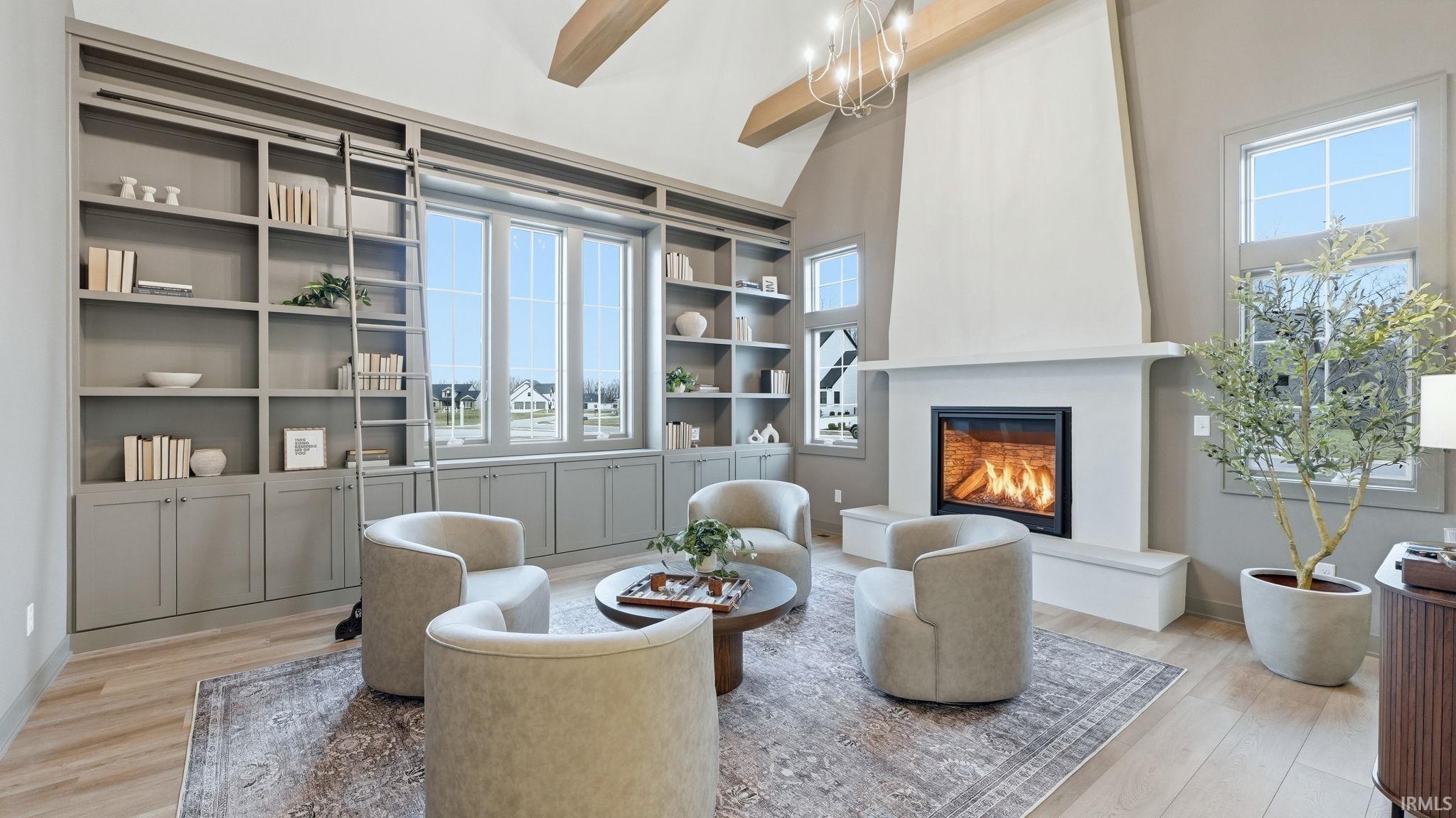 Sitting room with a fireplace, light wood-type flooring, lofted ceiling, a chandelier, and built in features
