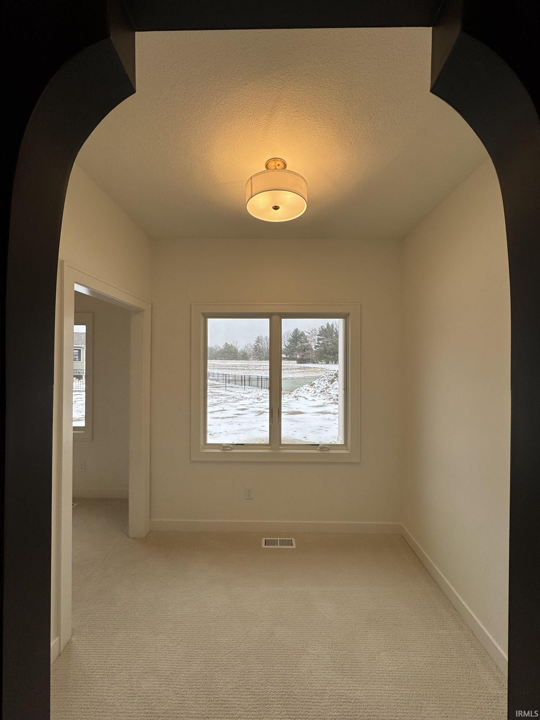 Sitting room with arched walkways, light colored carpet, and a textured ceiling