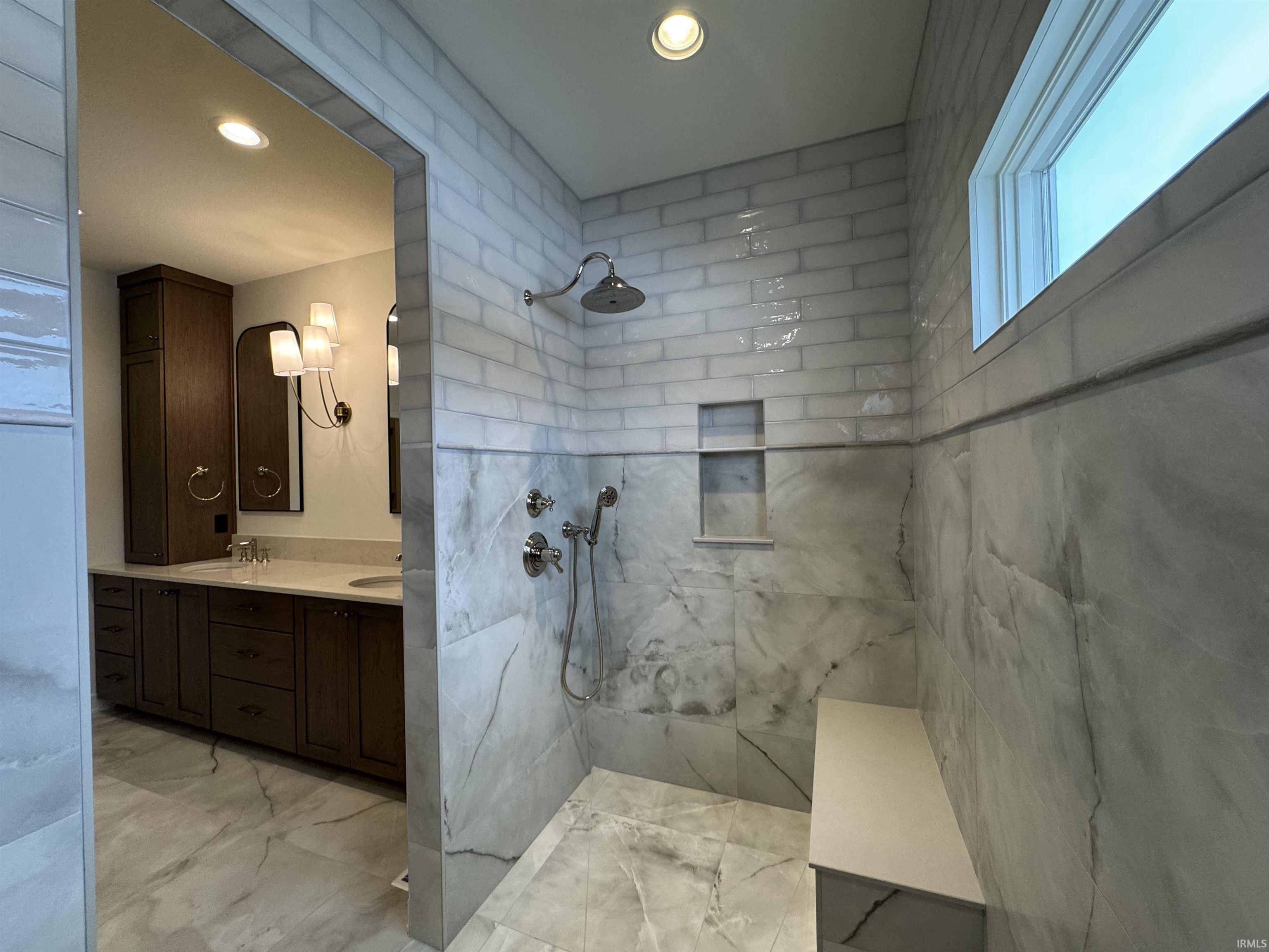Bathroom with double vanity, a marble finish shower, light marble finish flooring, and recessed lighting