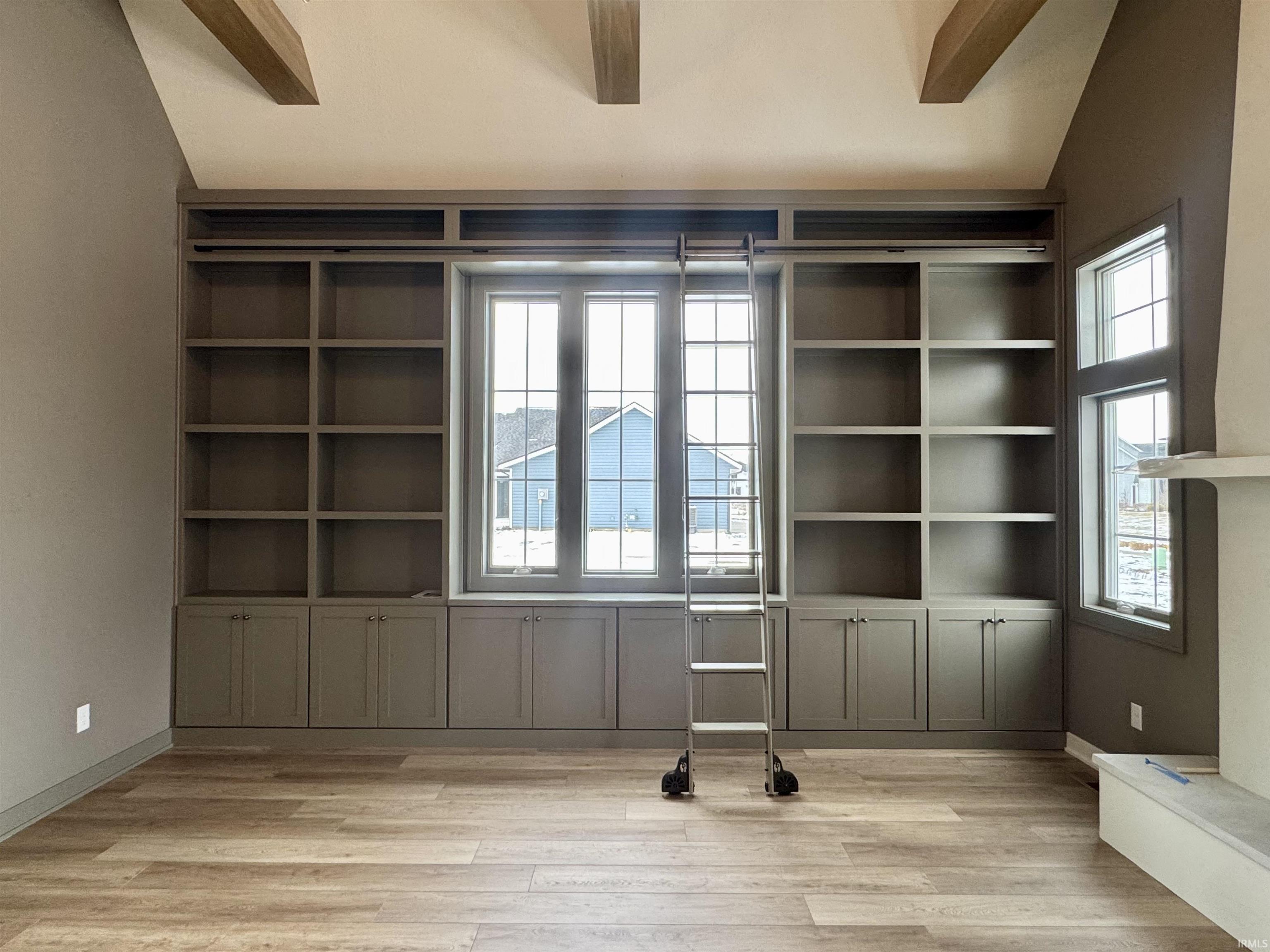 Den featuring built in shelves, vaulted ceiling with beams, ceiling fan, and light wood-type flooring
