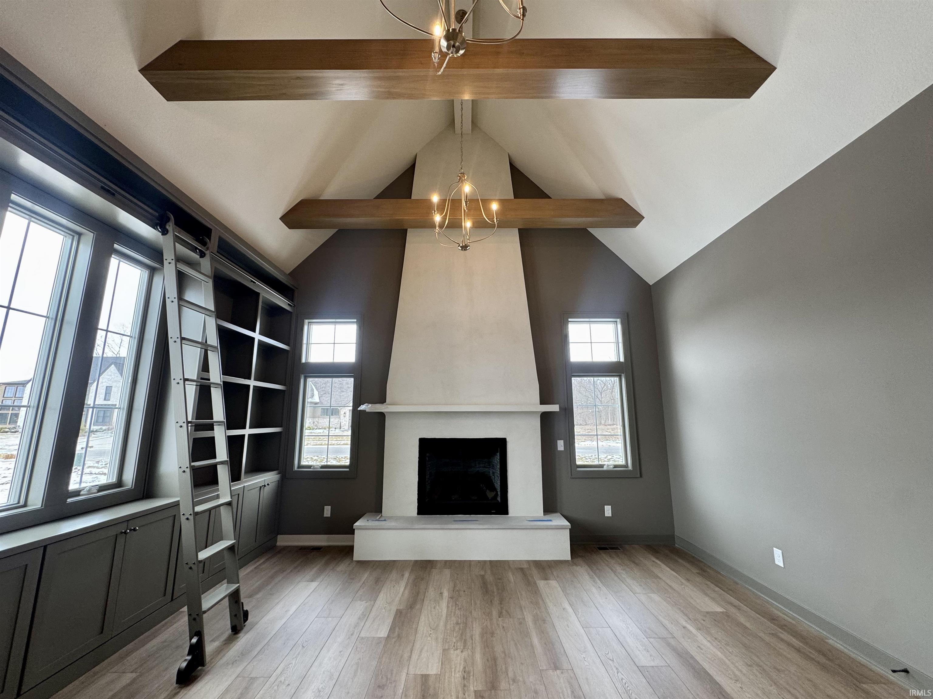 Den featuring a chandelier, light wood-style flooring, and a large fireplace