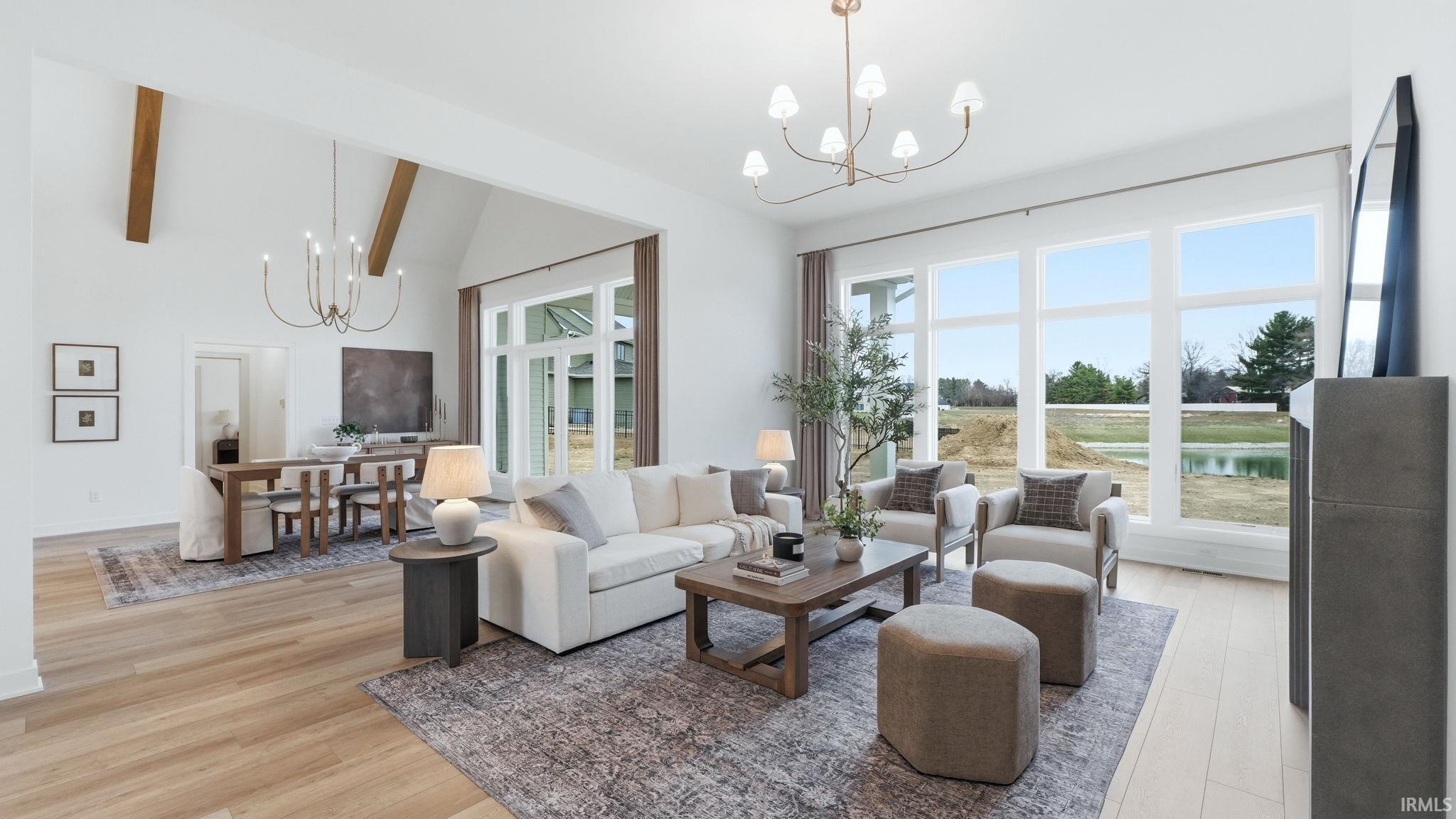 Living area with hanging lights, light wood-style flooring, and lofted ceiling