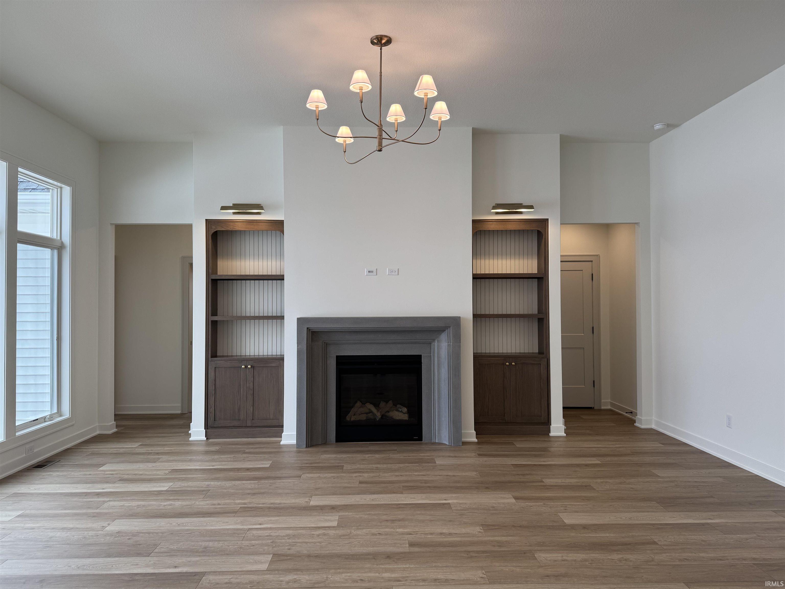 Unfurnished living room featuring suspended lighting, a fireplace, and light wood-style flooring