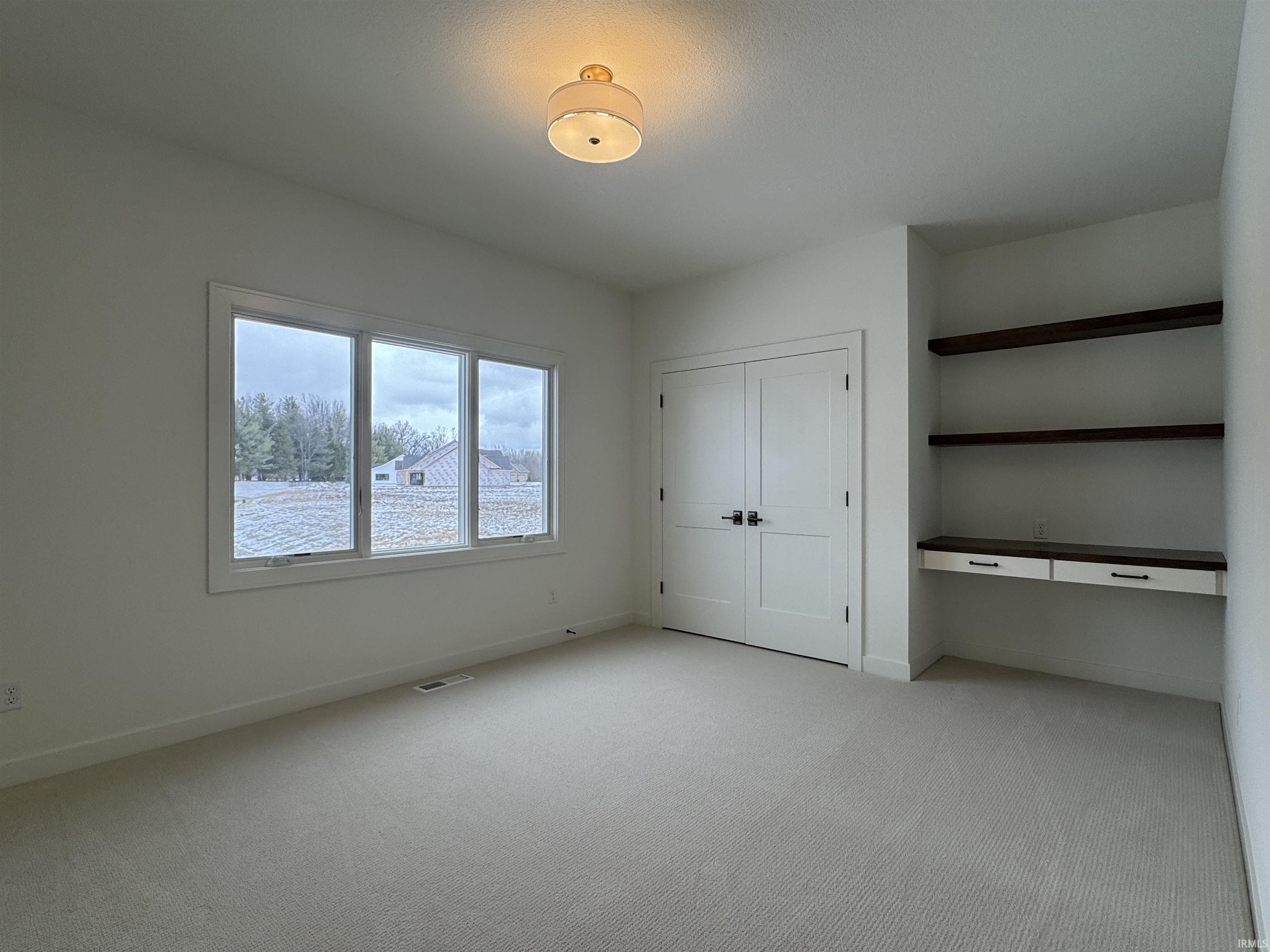 Bedroom #2 with built in desk, light carpet, and a closet
