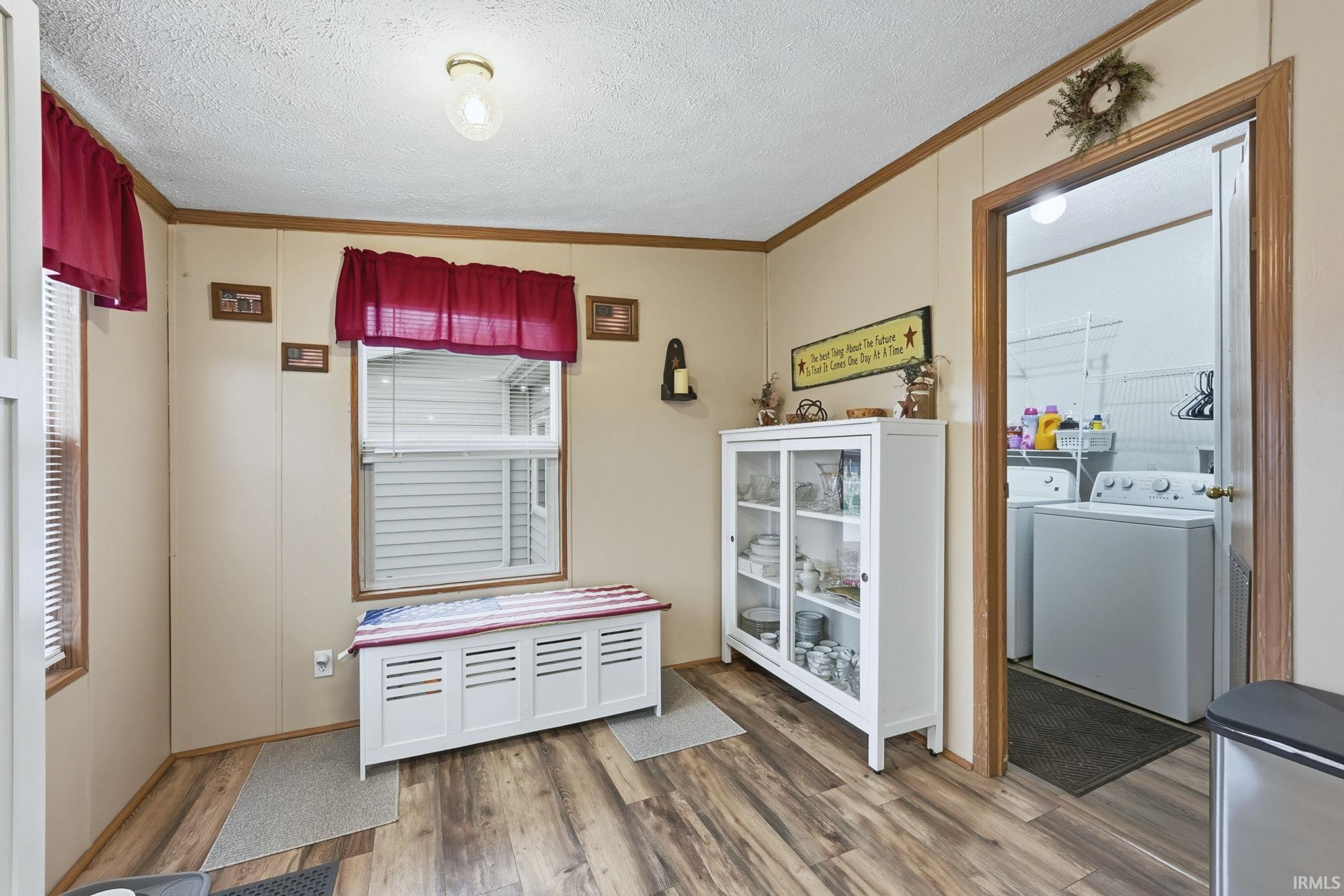 Dining area featuring a textured ceiling, ornamental molding, light wood finished floors, and washer and clothes dryer