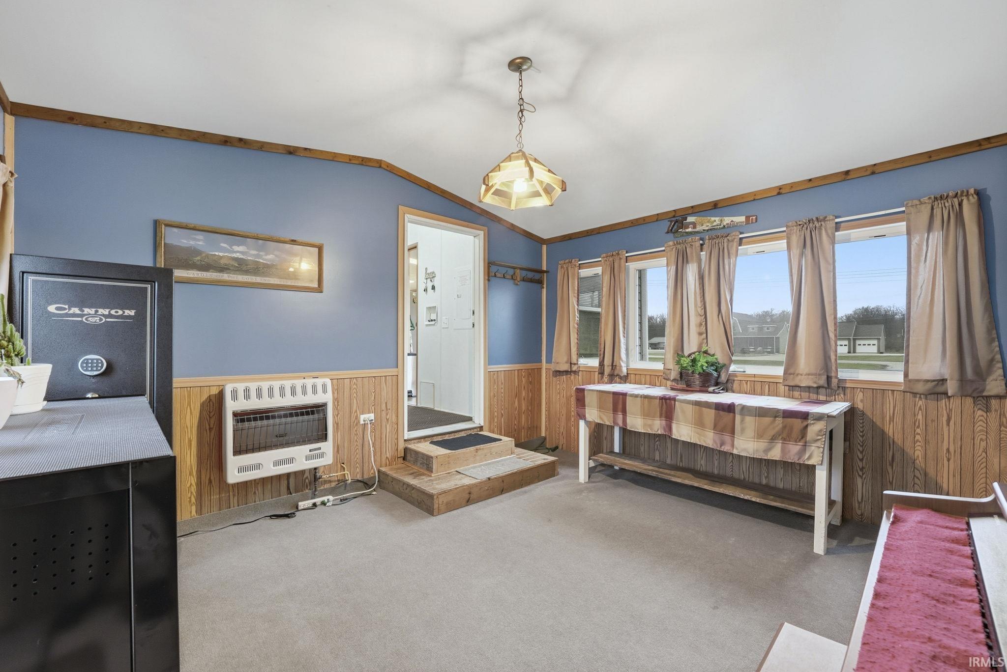 Bedroom with lofted ceiling, heating unit, a wainscoted wall, carpet flooring, and wooden walls