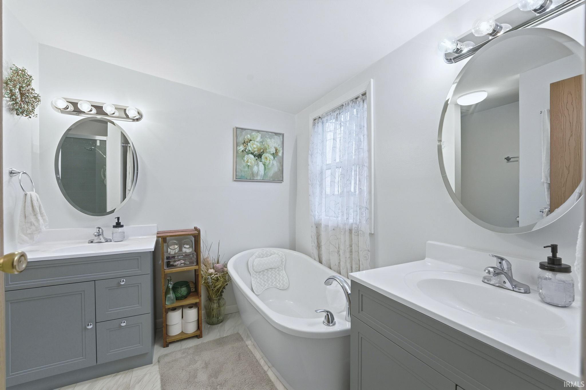 Full bathroom featuring two vanities and a freestanding tub