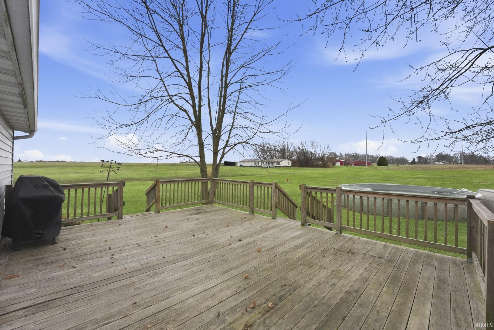 Wooden terrace featuring a view of rural / pastoral area, a grill, and a yard