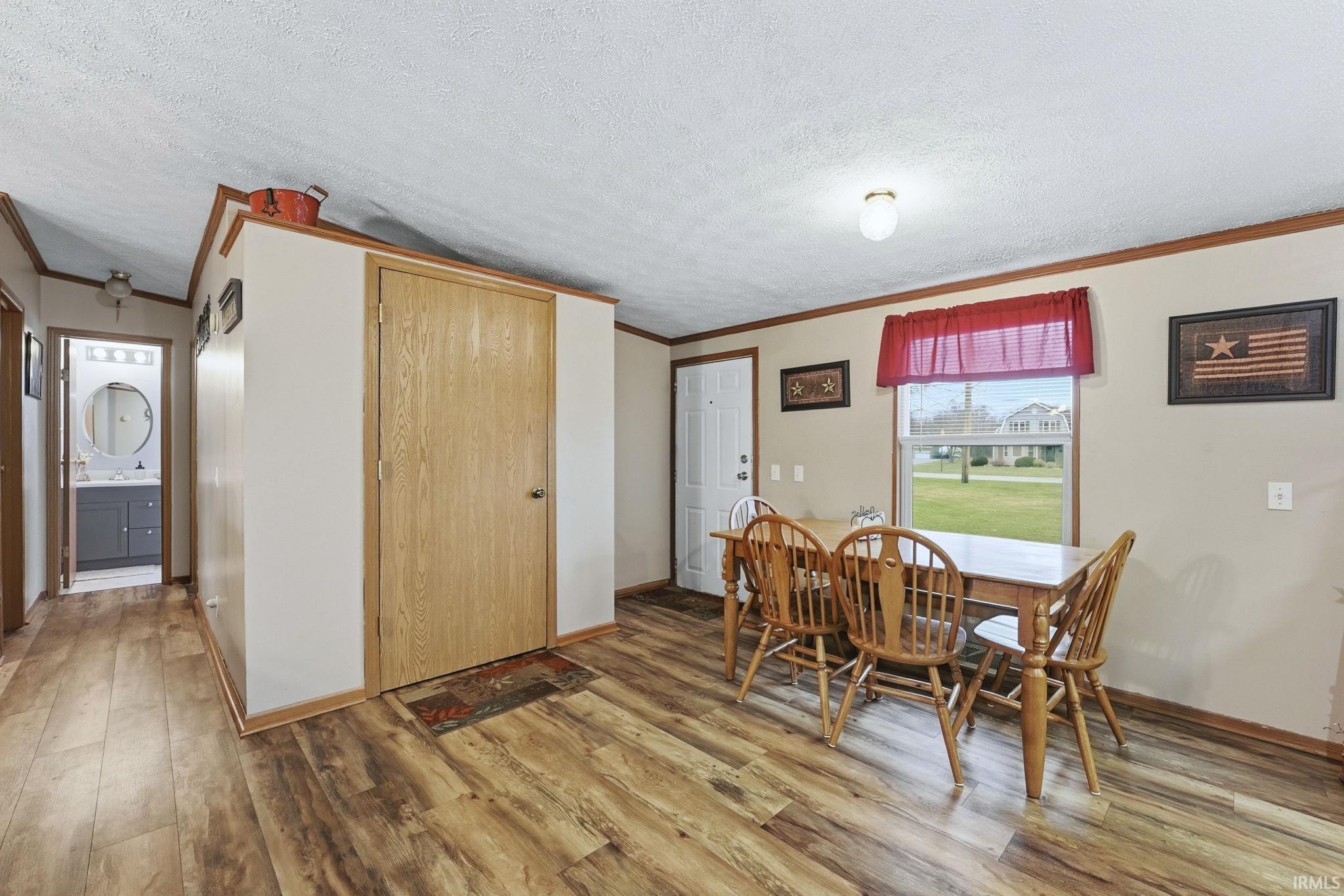 Dining area featuring a textured ceiling, ornamental molding, and light wood finished floors
