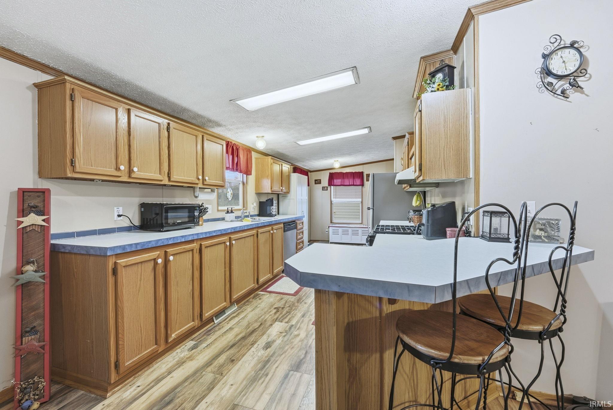 Kitchen featuring a peninsula, a breakfast bar, light countertops, light wood-style flooring, and lofted ceiling