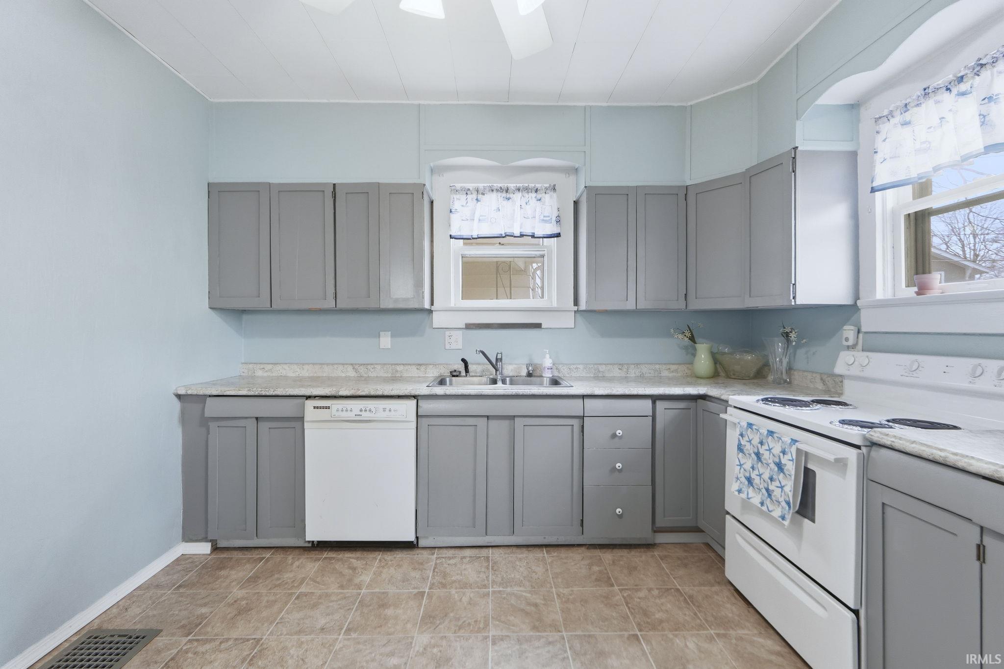 Kitchen with gray cabinetry, white appliances, and light countertops