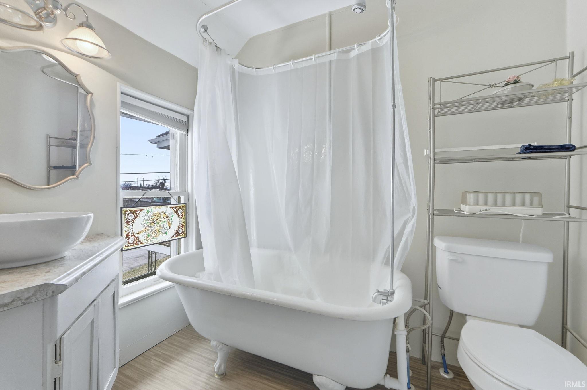 Bathroom with vanity, light wood-style flooring, and shower / tub combo with curtain