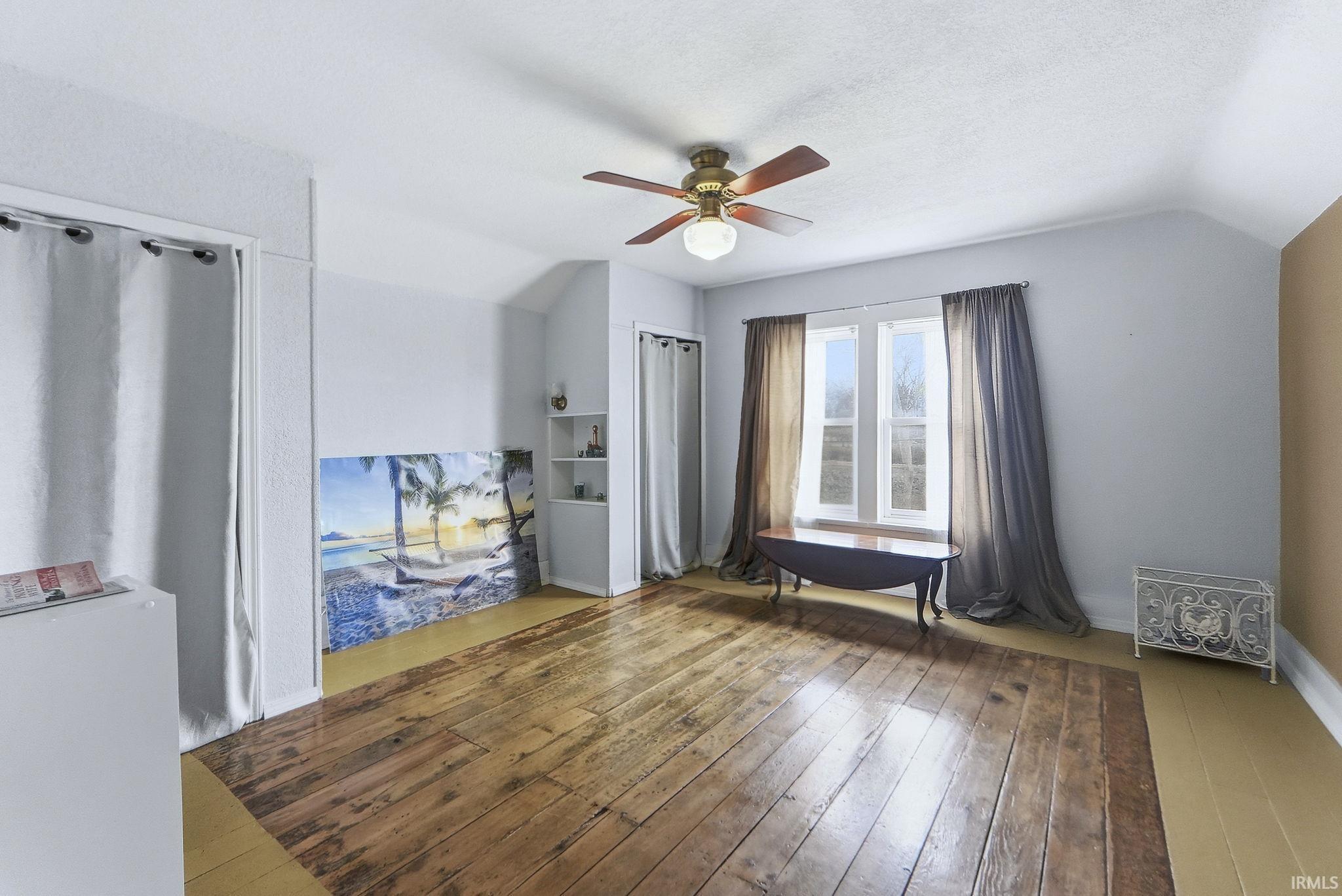 Spare room with a ceiling fan, hardwood / wood-style floors, lofted ceiling, and a textured ceiling