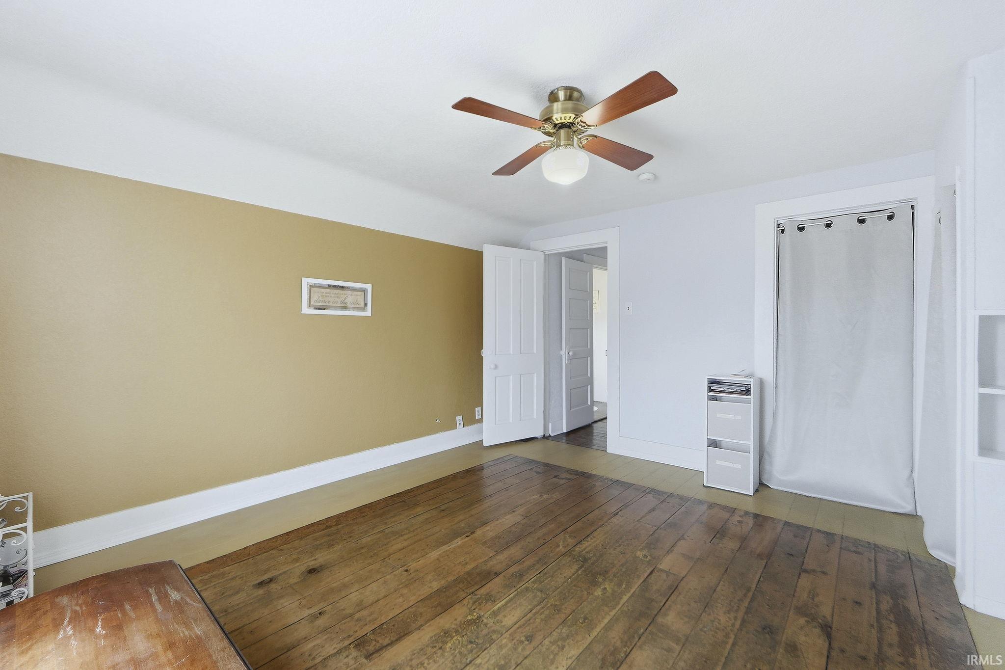 Unfurnished bedroom featuring a ceiling fan and dark wood-style flooring