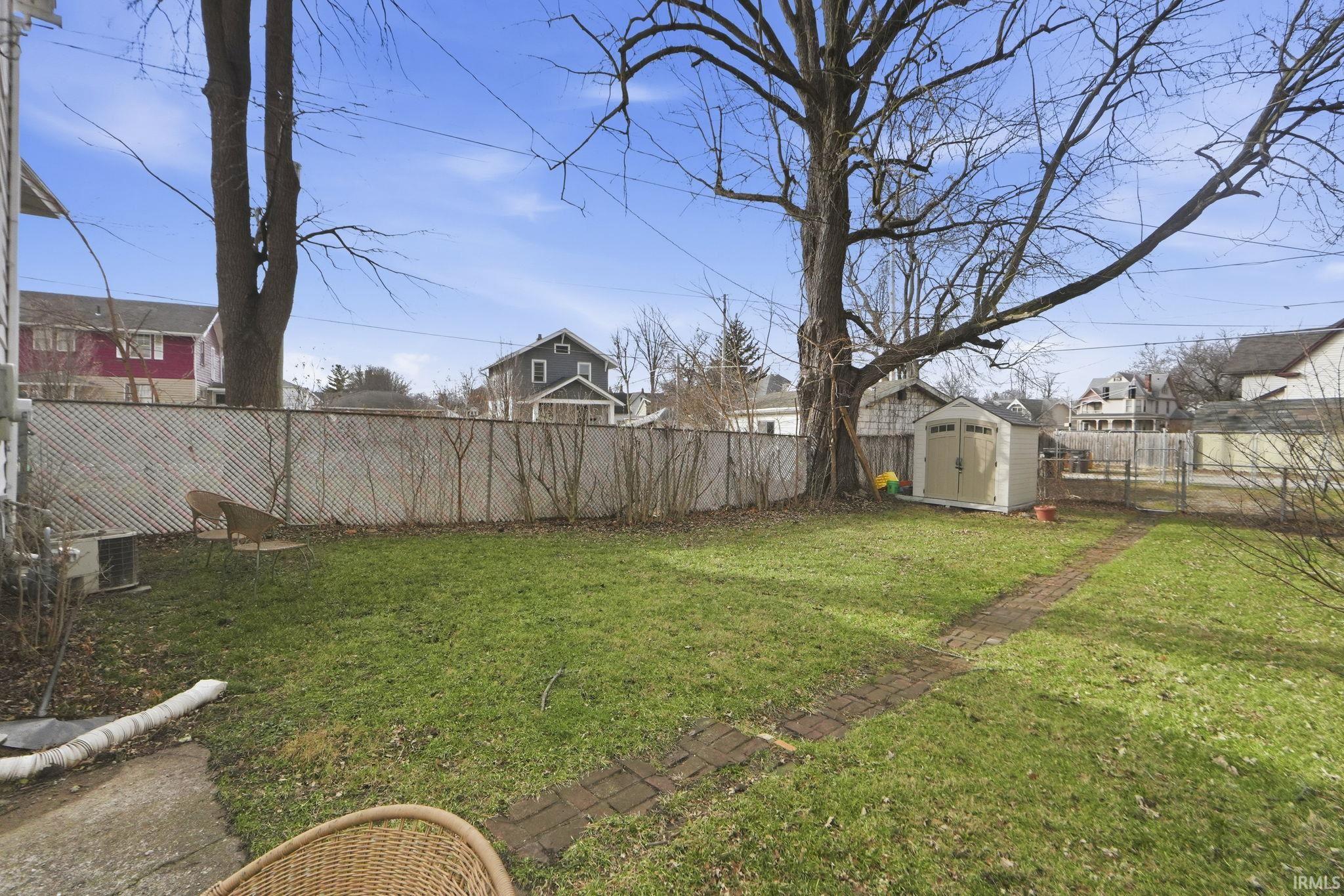 Fenced backyard with a shed and a residential view