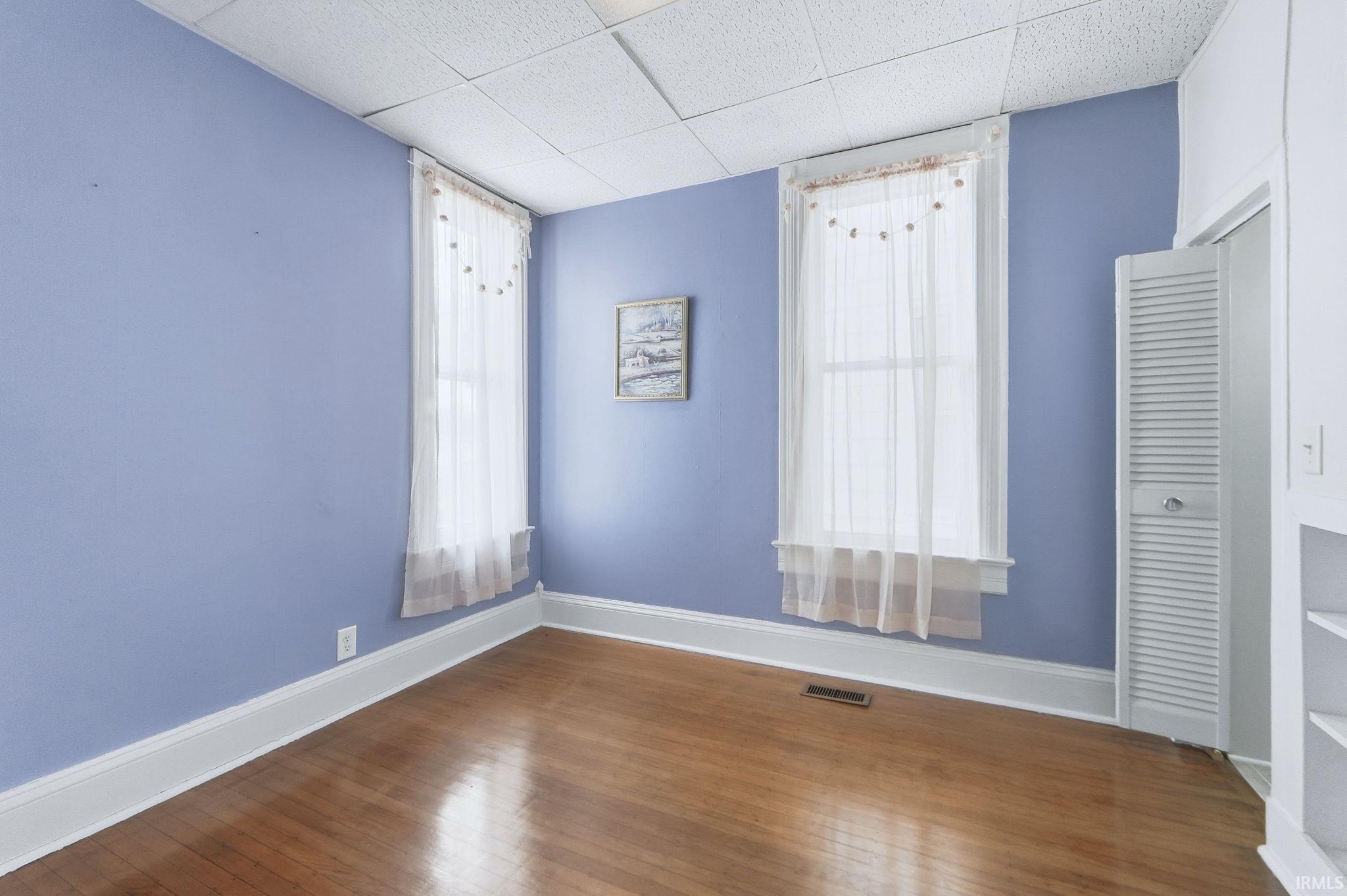 Unfurnished room featuring wood finished floors and a paneled ceiling