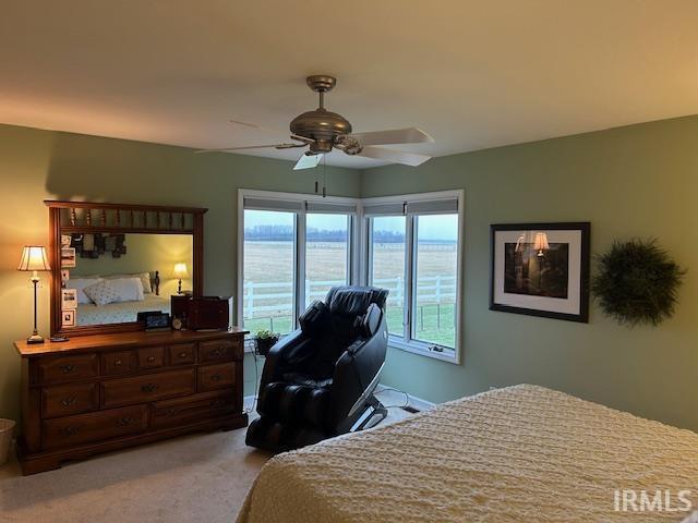 Bedroom featuring an office area, a ceiling fan, and light colored carpet