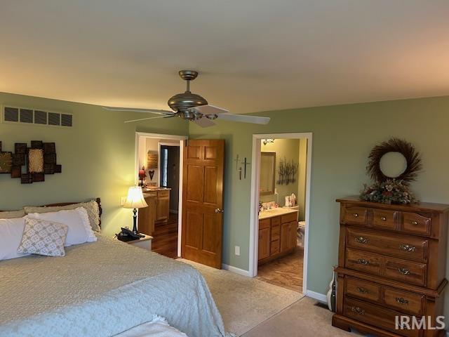 Bedroom featuring light carpet, ceiling fan, and connected bathroom