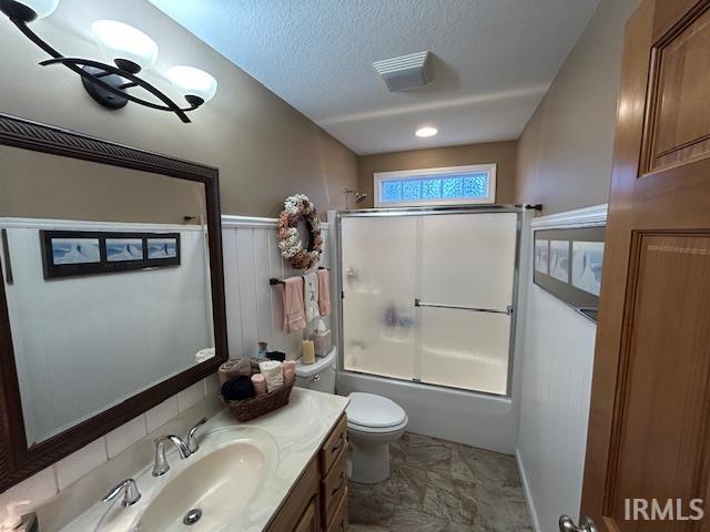 Full bath featuring shower / bath combination with glass door, vanity, and a textured ceiling