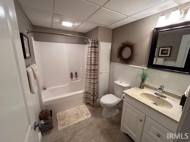 Full bathroom featuring vanity, shower / bath combo with shower curtain, and a drop ceiling