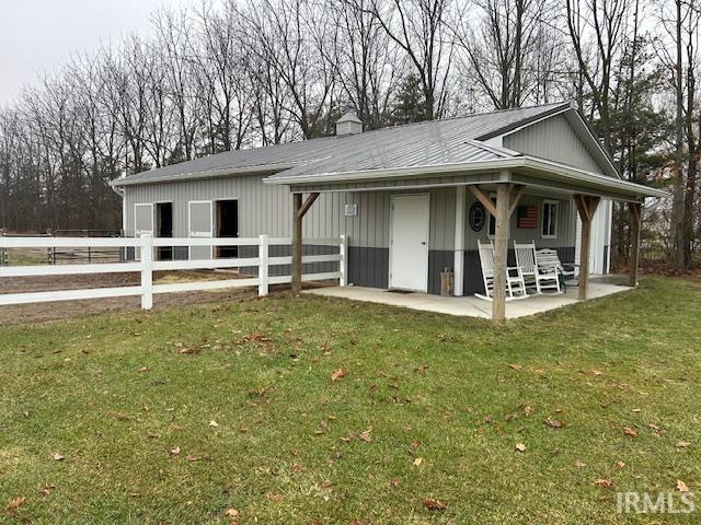 View of front of property featuring a porch, a chimney, an exterior structure, and an outdoor structure