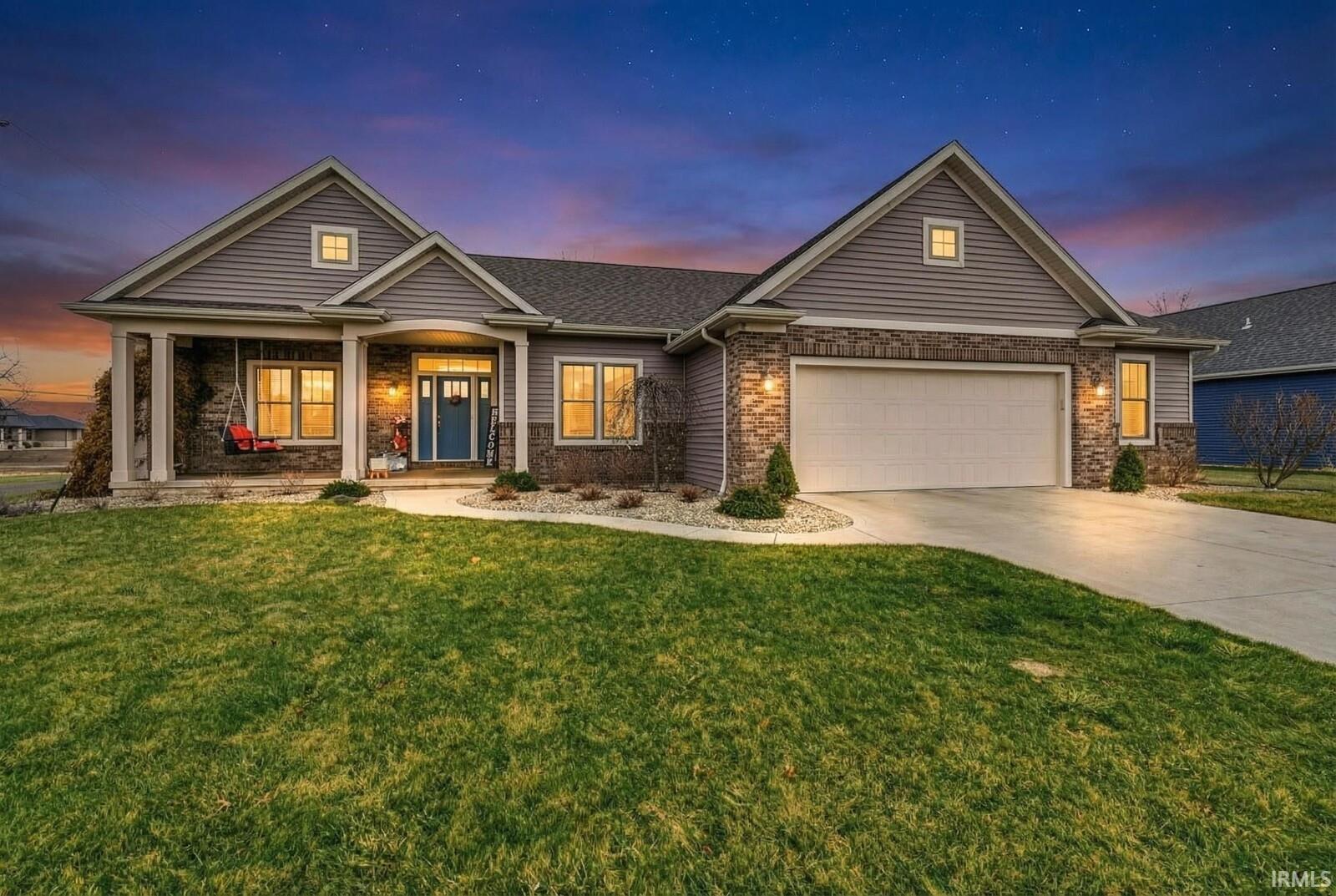 View of front of house with brick siding, a porch, driveway, and a front yard
