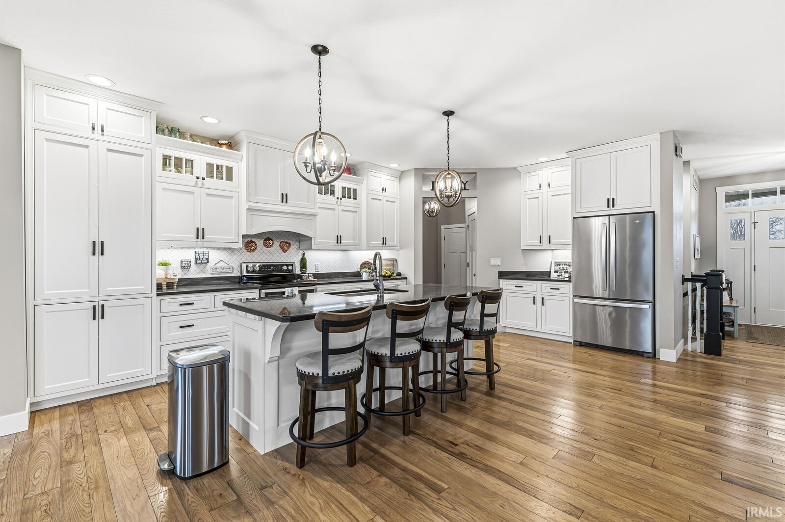 Kitchen with stainless steel appliances, glass insert cabinets, a breakfast bar area, white cabinetry, and an island with sink