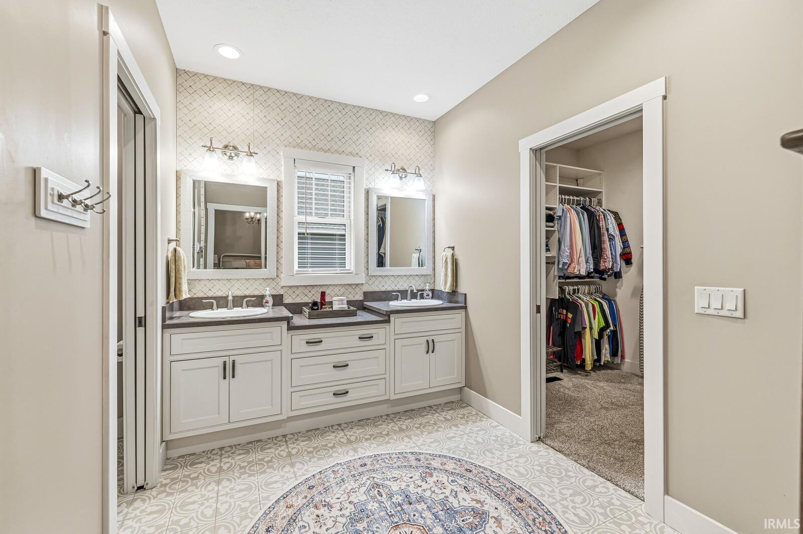 Full bath featuring double vanity, a spacious closet, and recessed lighting