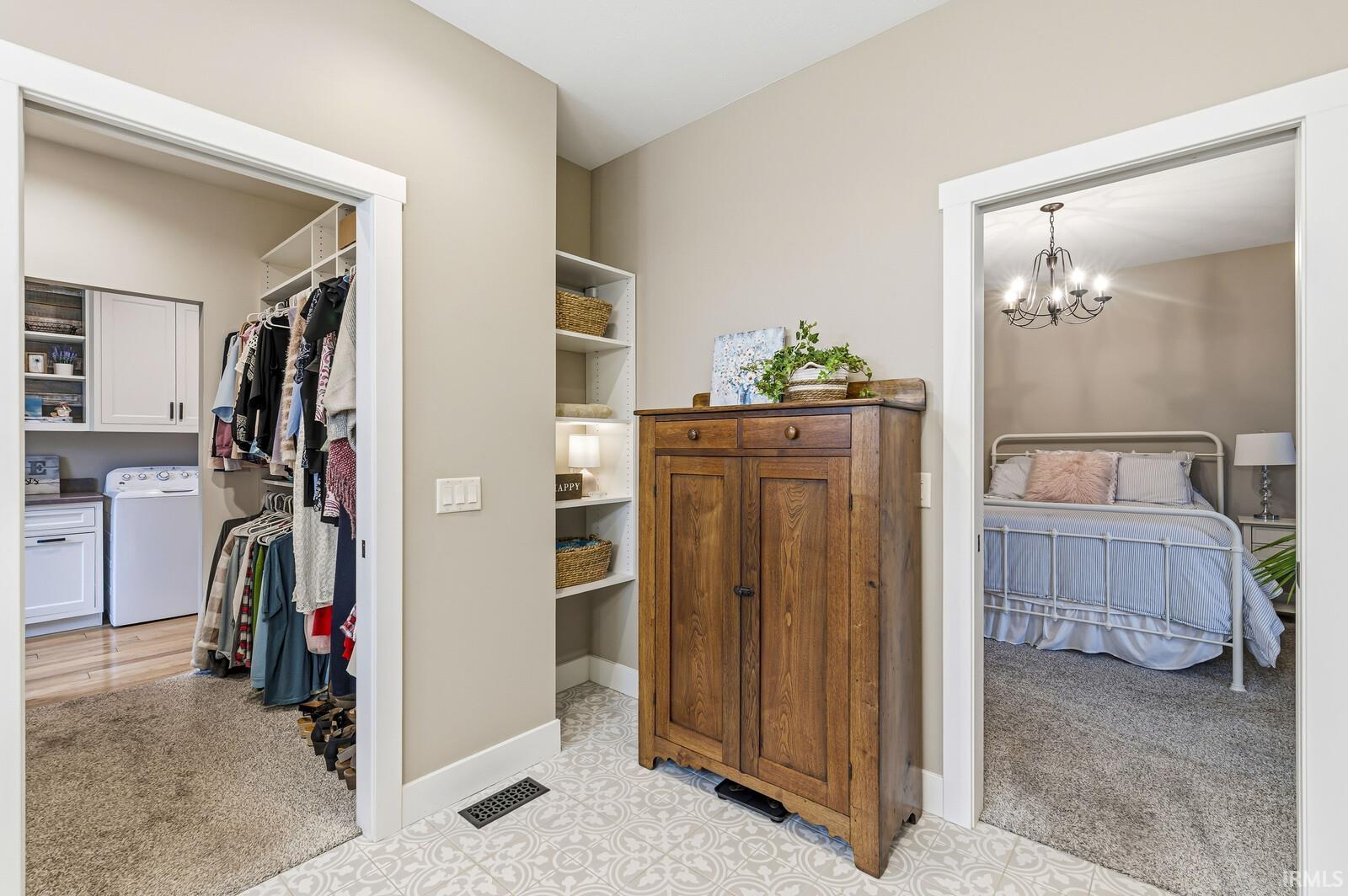 Bedroom with light colored carpet, washer / clothes dryer, a walk in closet, and a chandelier