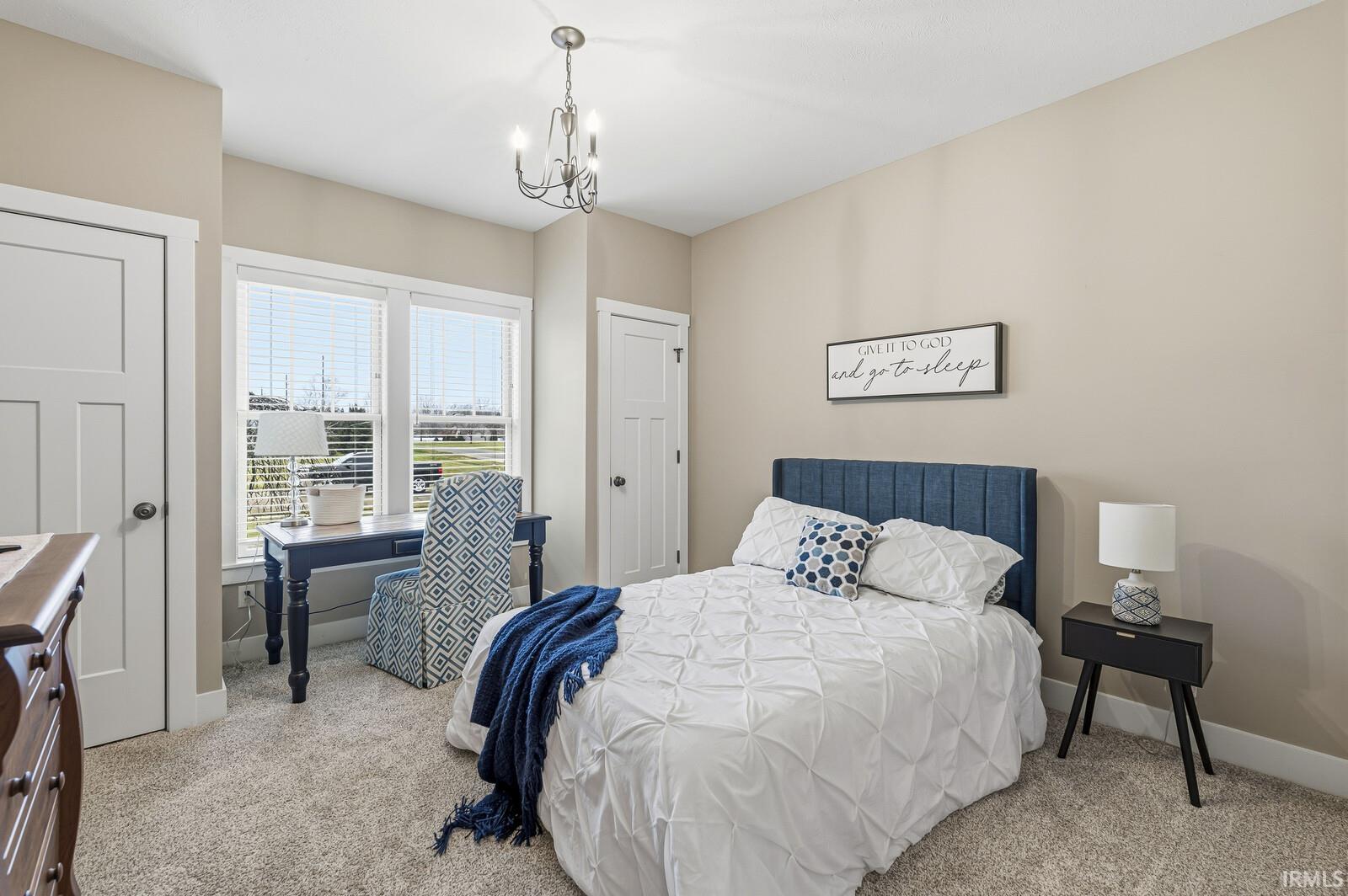 Bedroom featuring light colored carpet and a chandelier
