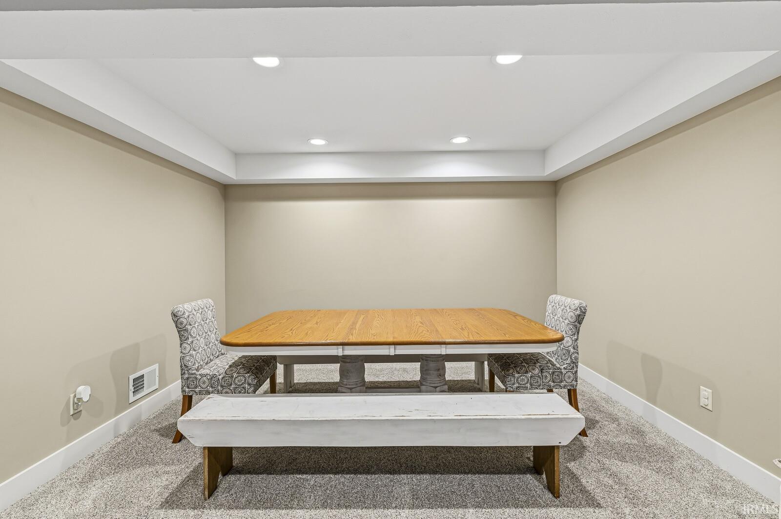 Dining room with light colored carpet and recessed lighting