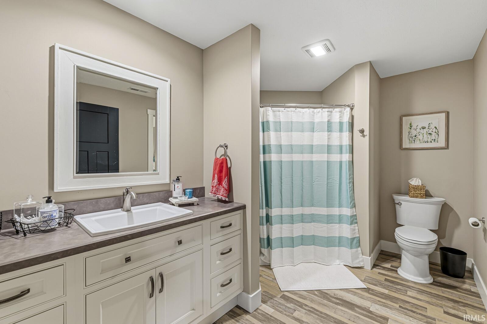 Full bath with a stall shower, vanity, and light wood-type flooring