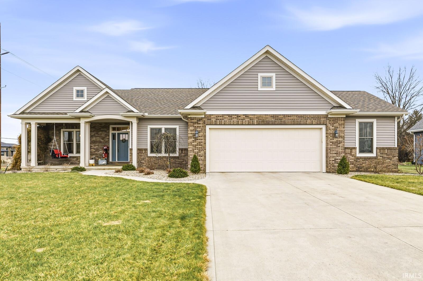 View of front of property with a shingled roof, a front lawn, concrete driveway, and covered porch