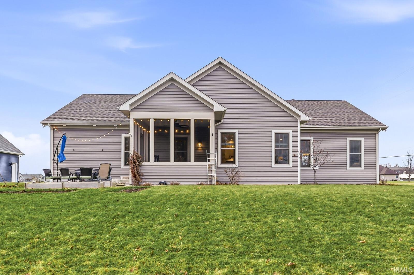 Rear view of property featuring roof with shingles, a yard, and a patio