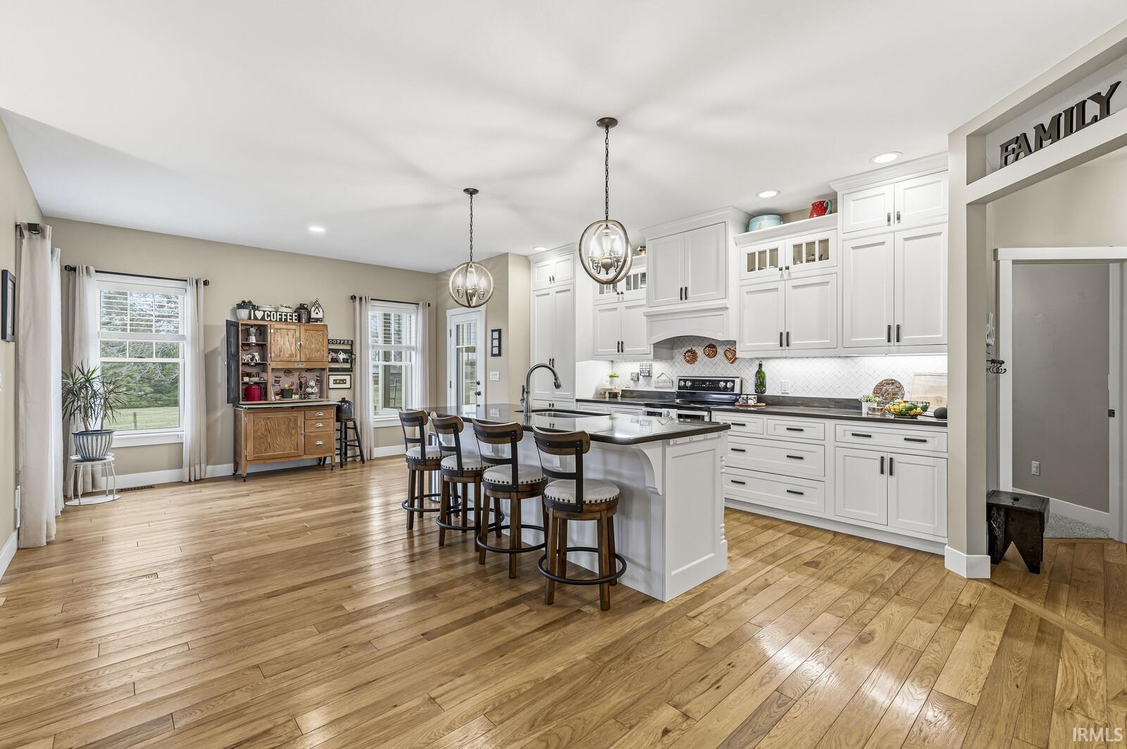 Kitchen featuring glass insert cabinets, a breakfast bar, pendant lighting, white cabinets, and light wood finished floors