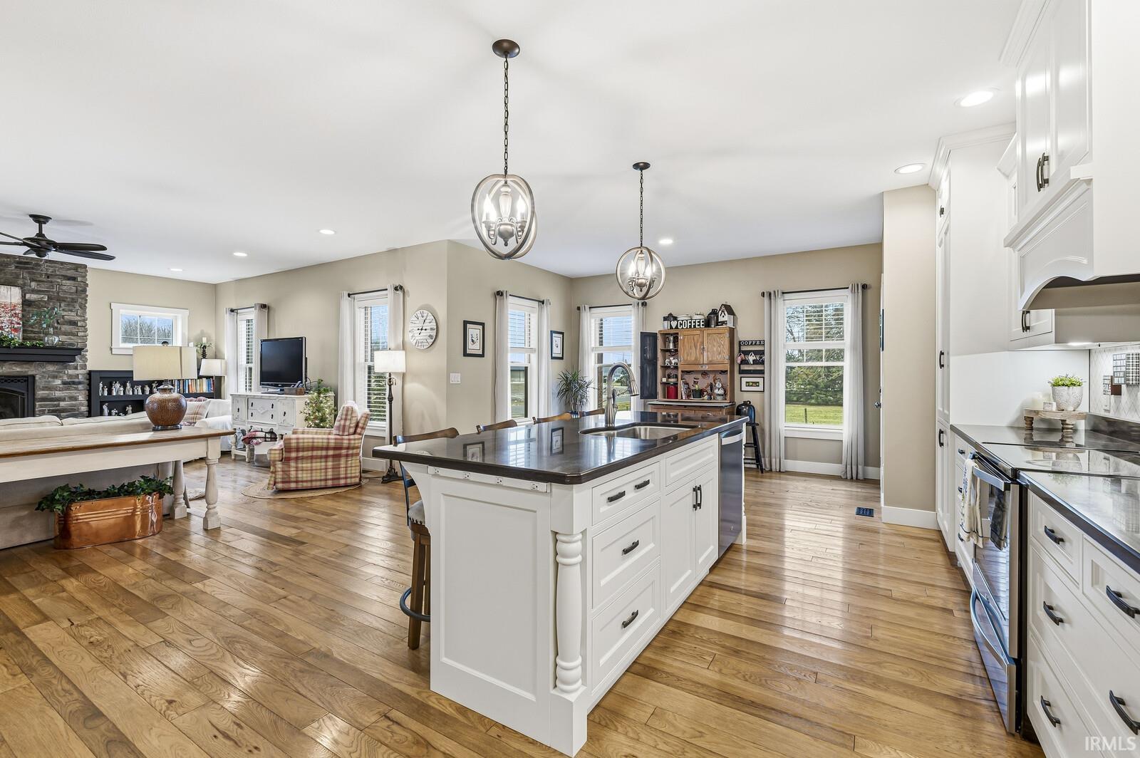 Kitchen featuring white cabinetry, open floor plan, a kitchen bar, recessed lighting, and stainless steel appliances