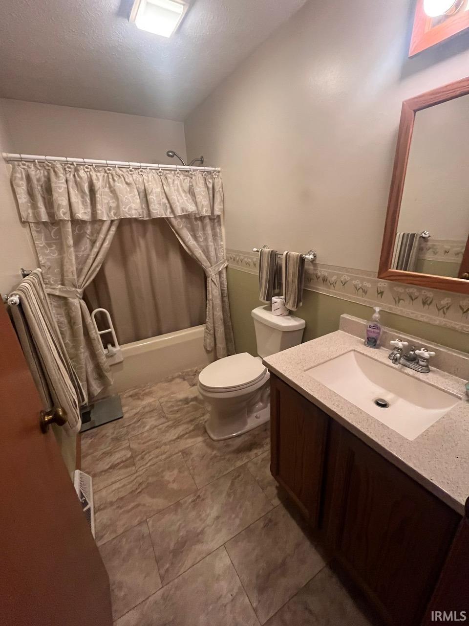 Full bathroom with vanity, shower / bath combination with curtain, and a textured ceiling